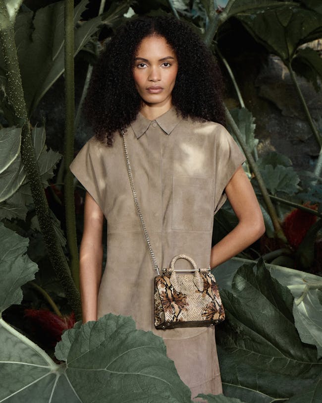 A woman with a handbag standing in front of plants