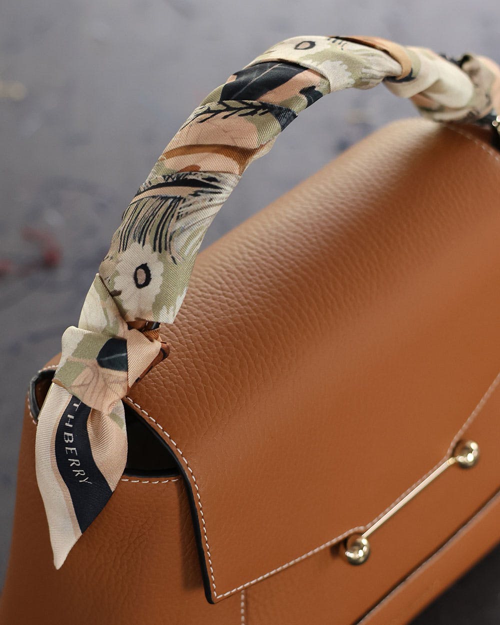 A brown purse with a bow on top of it