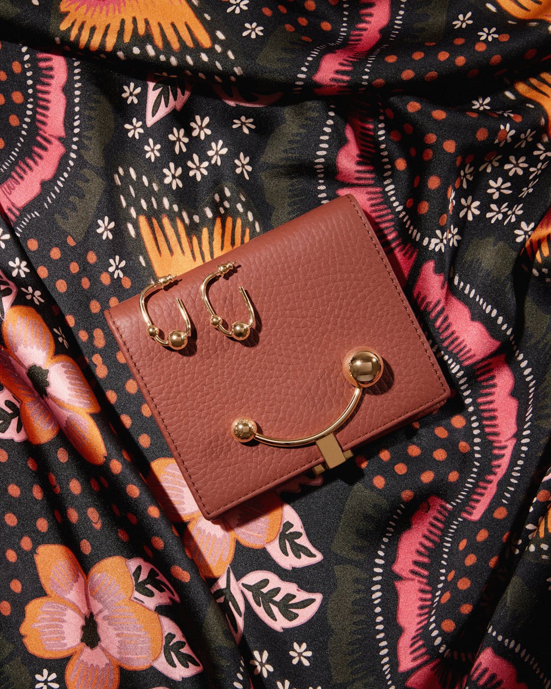 A pink purse sitting on top of a colorful cloth