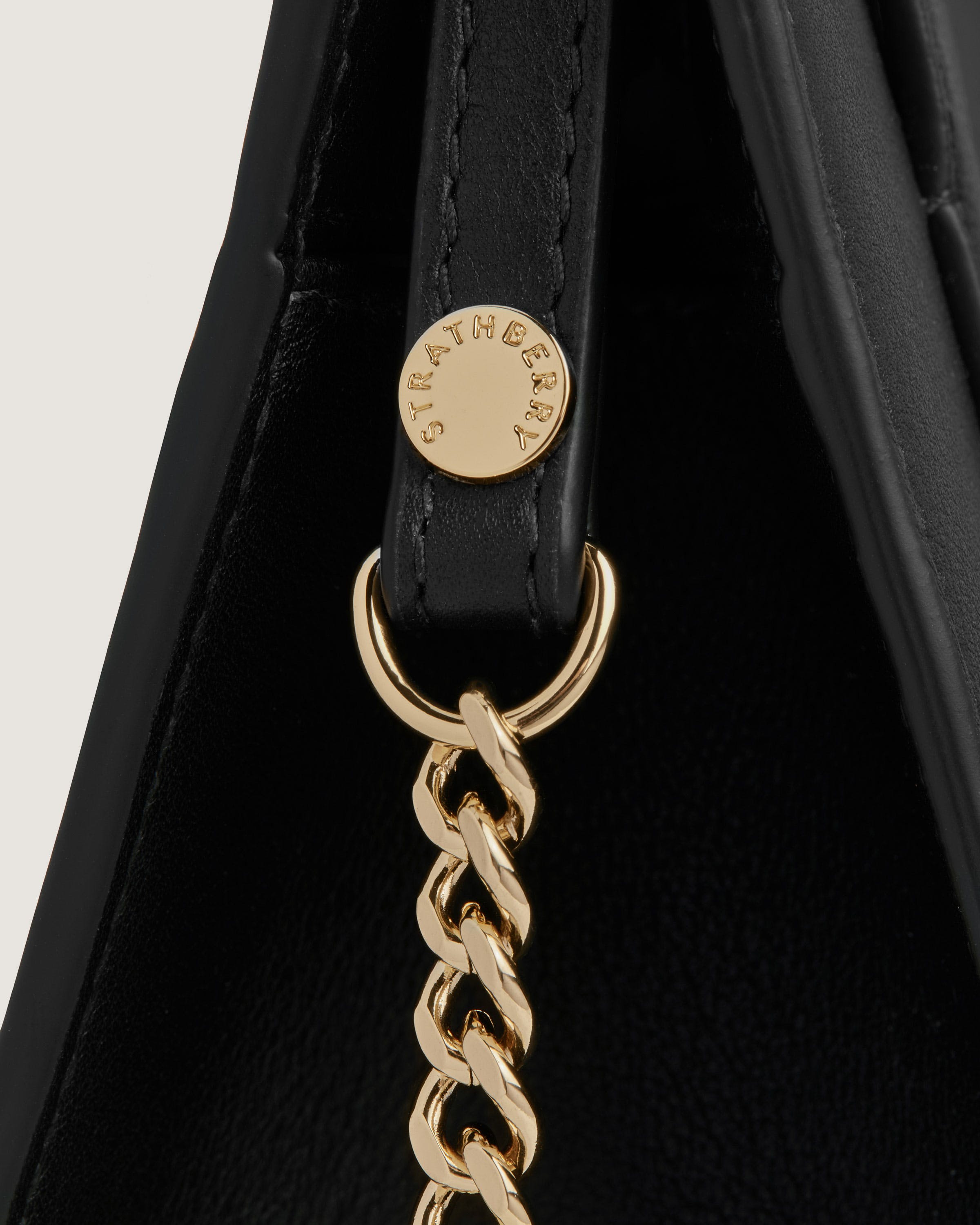 A black handbag with a gold chain hanging from it