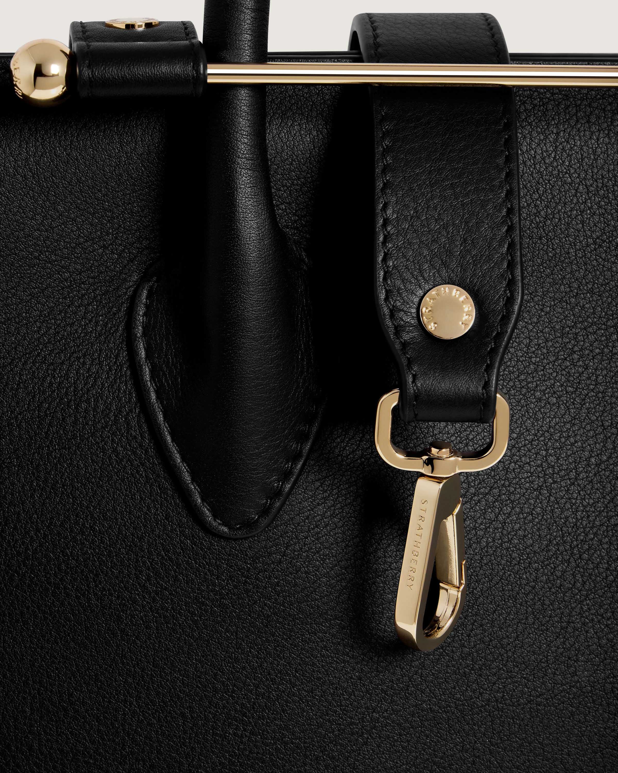 A close up of a black bag with a gold handle