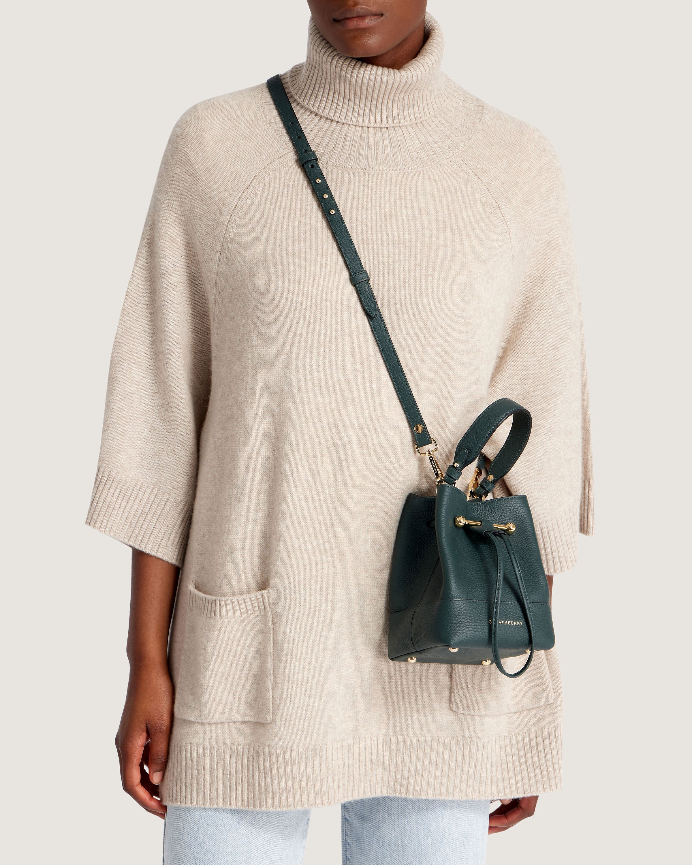 A woman wearing a white sweater and a green handbag