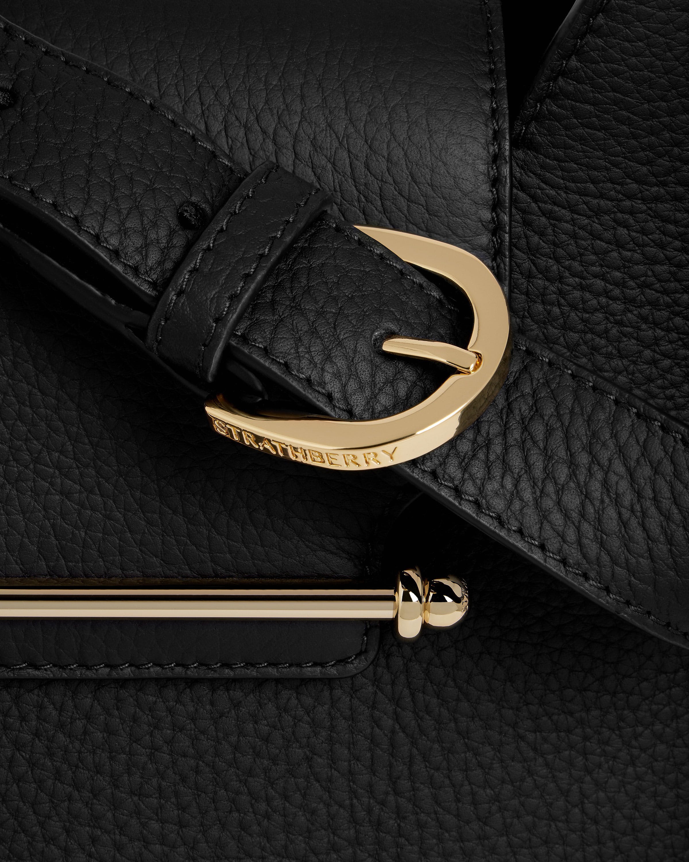 A close up of a black bag with a gold handle