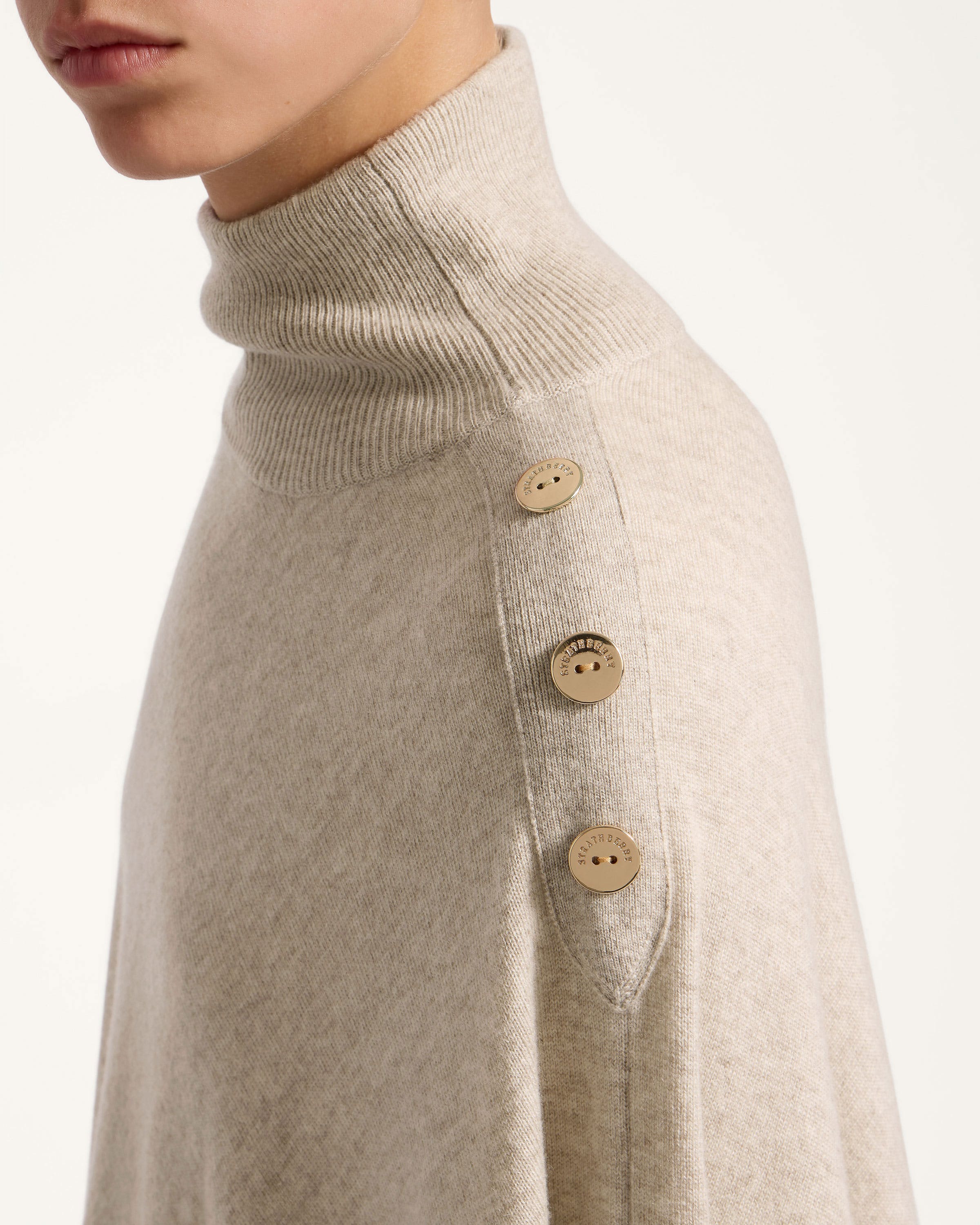 A woman wearing a turtle neck sweater with buttons