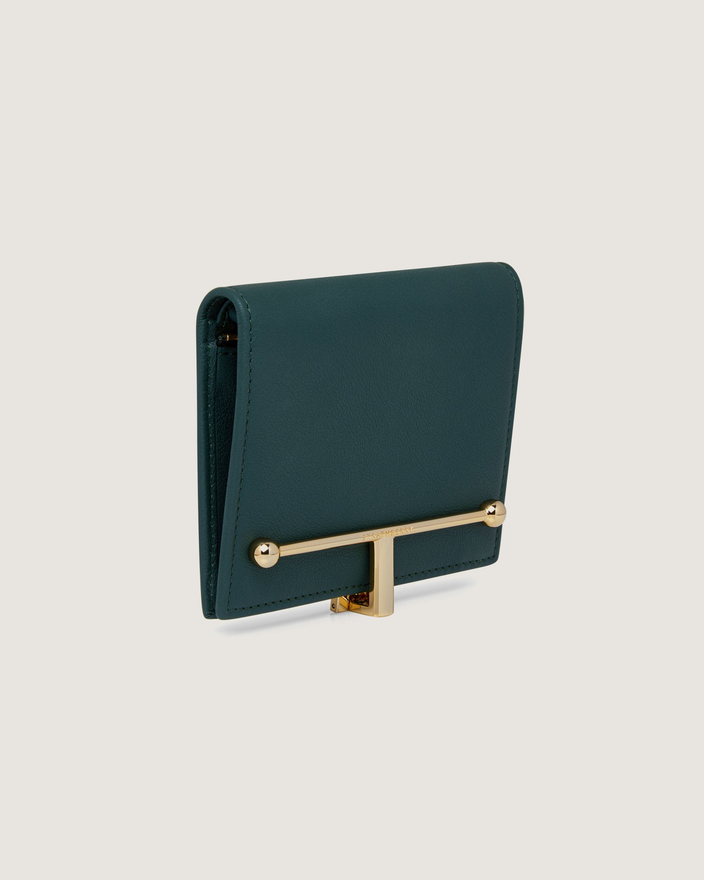 A green purse with a gold handle on a white background