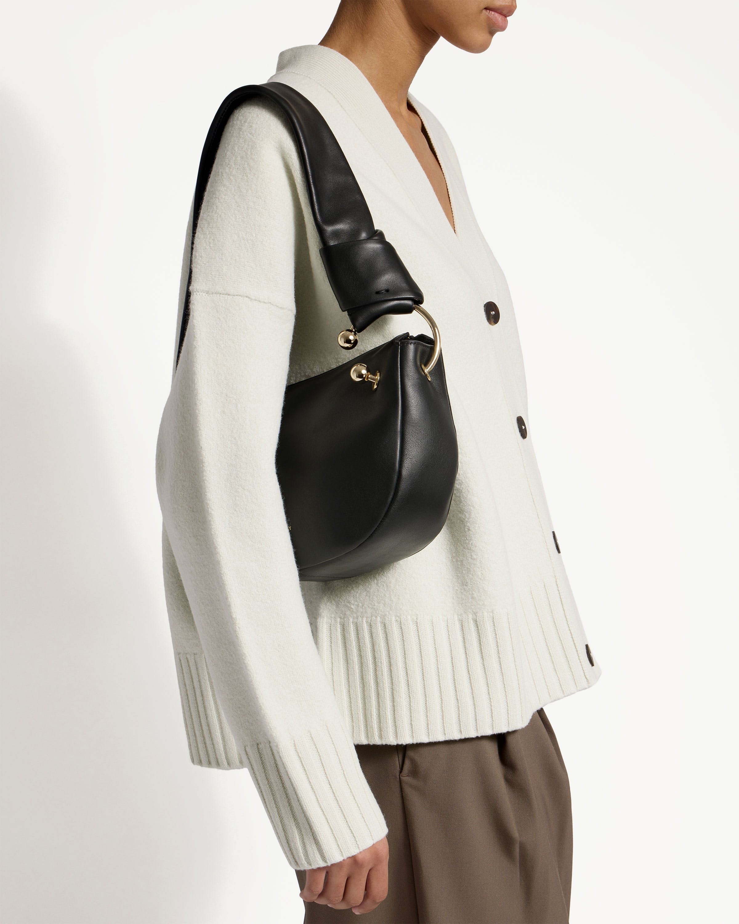 A woman wearing a white sweater and black handbag