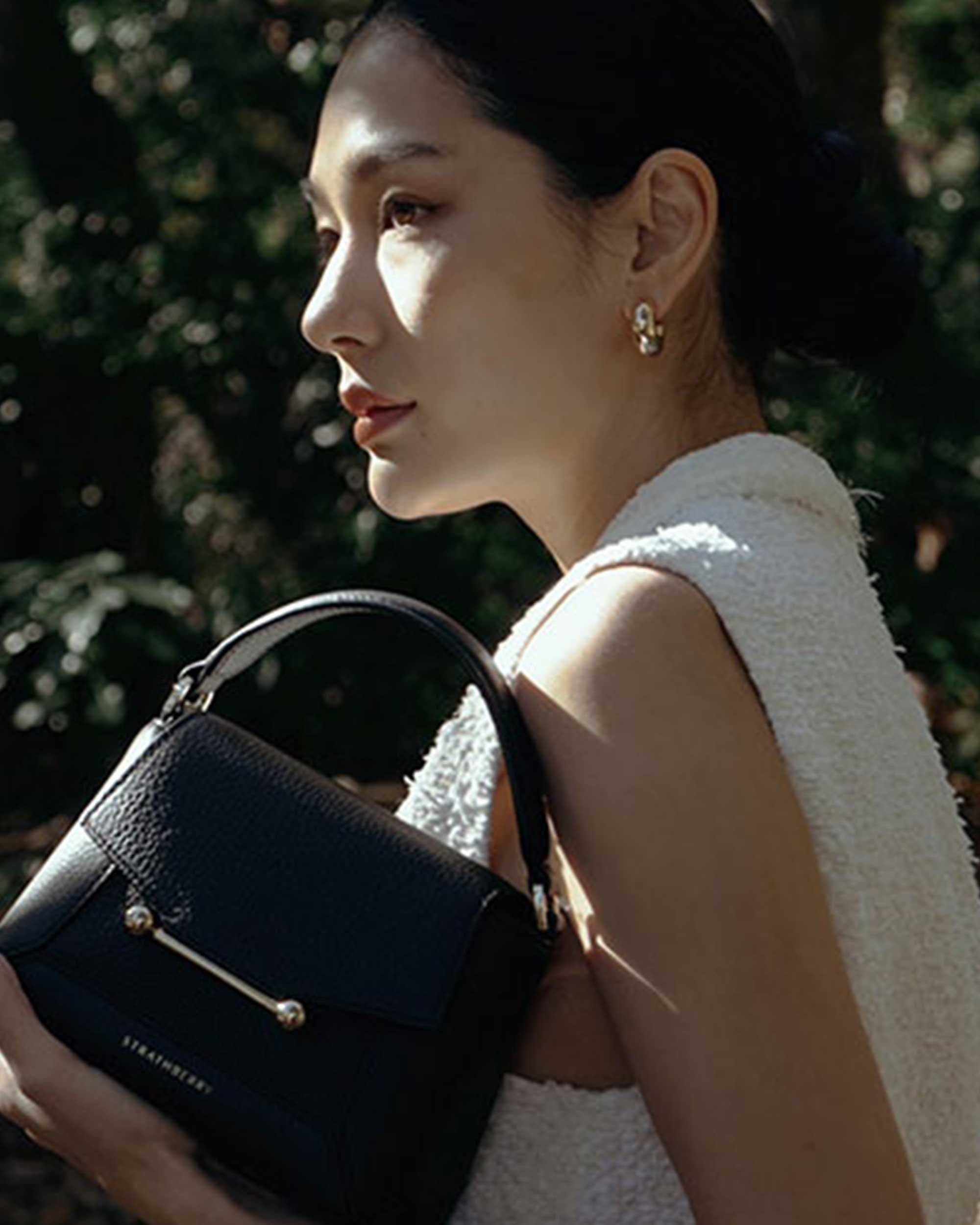 A woman in a white dress holding a black purse