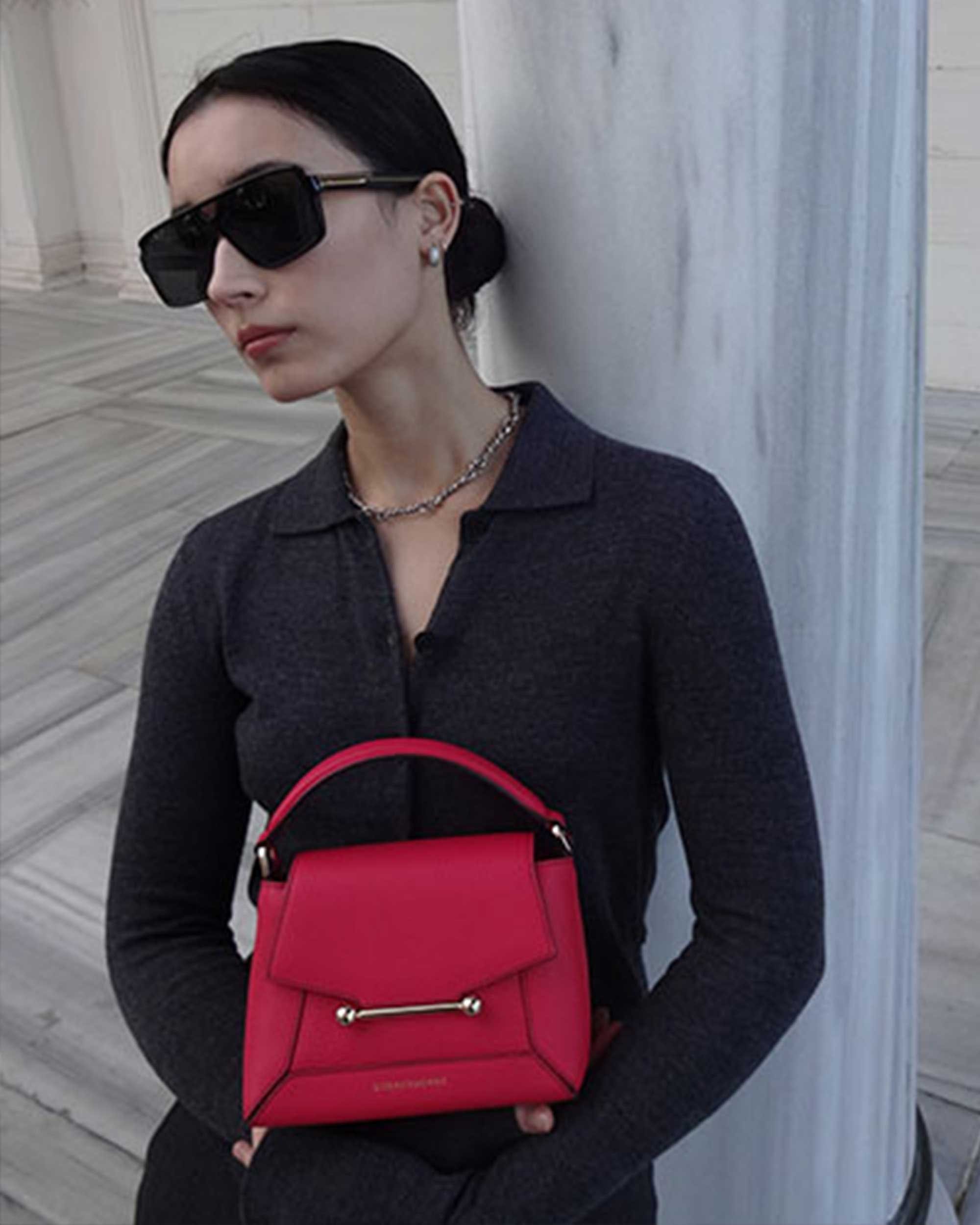 A woman wearing sunglasses and a red purse