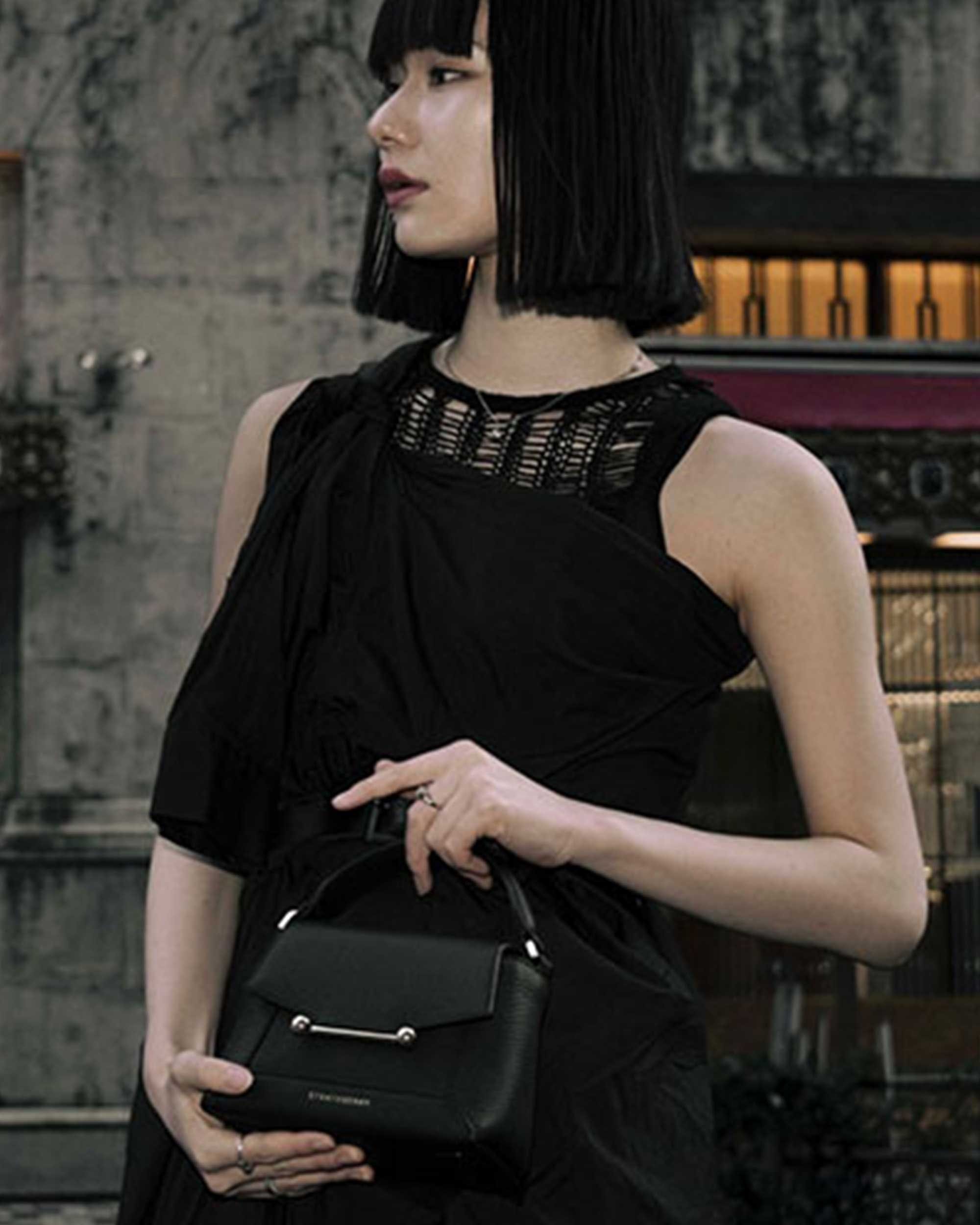 A woman in a black dress holding a black purse