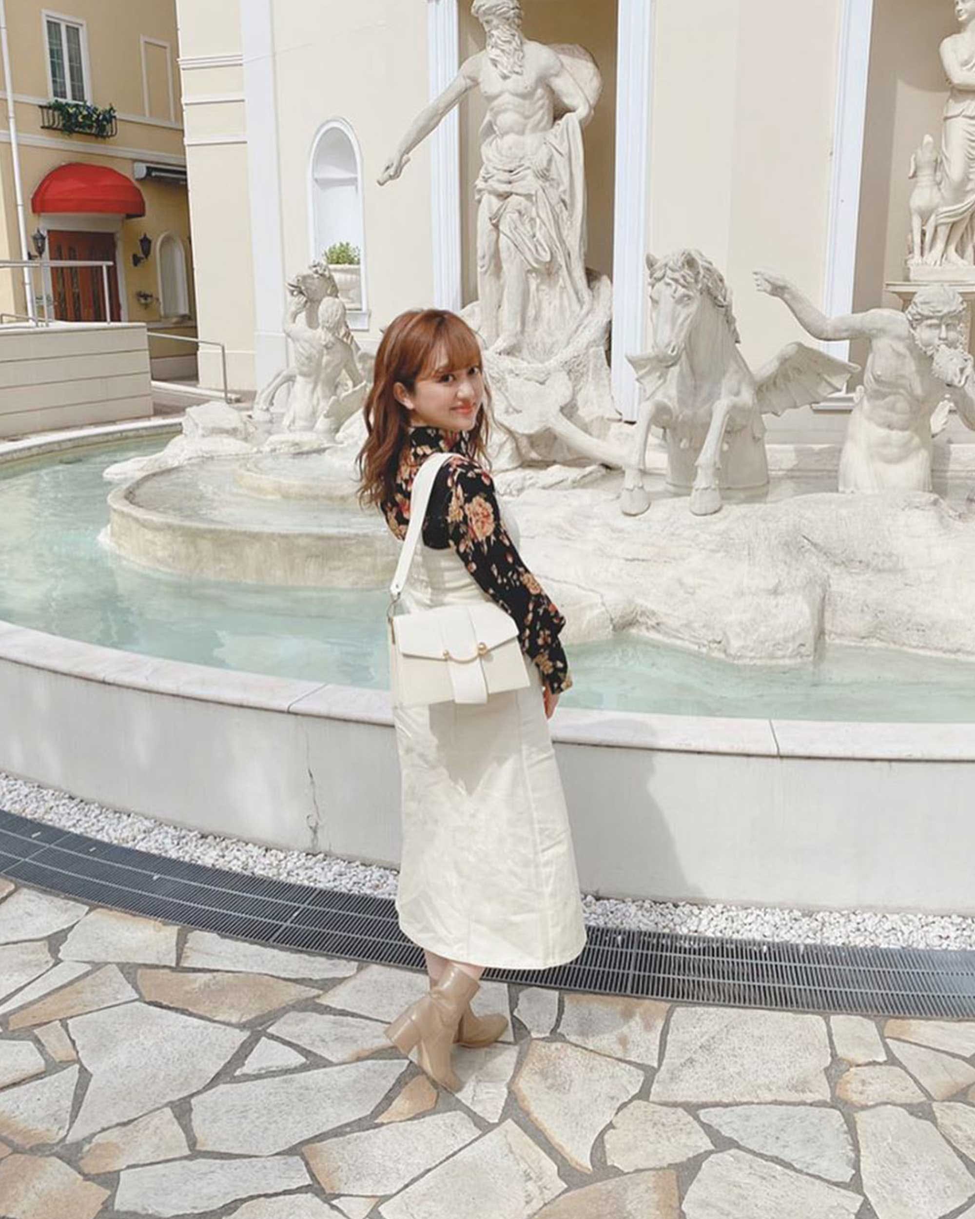 A little girl that is standing in front of a fountain