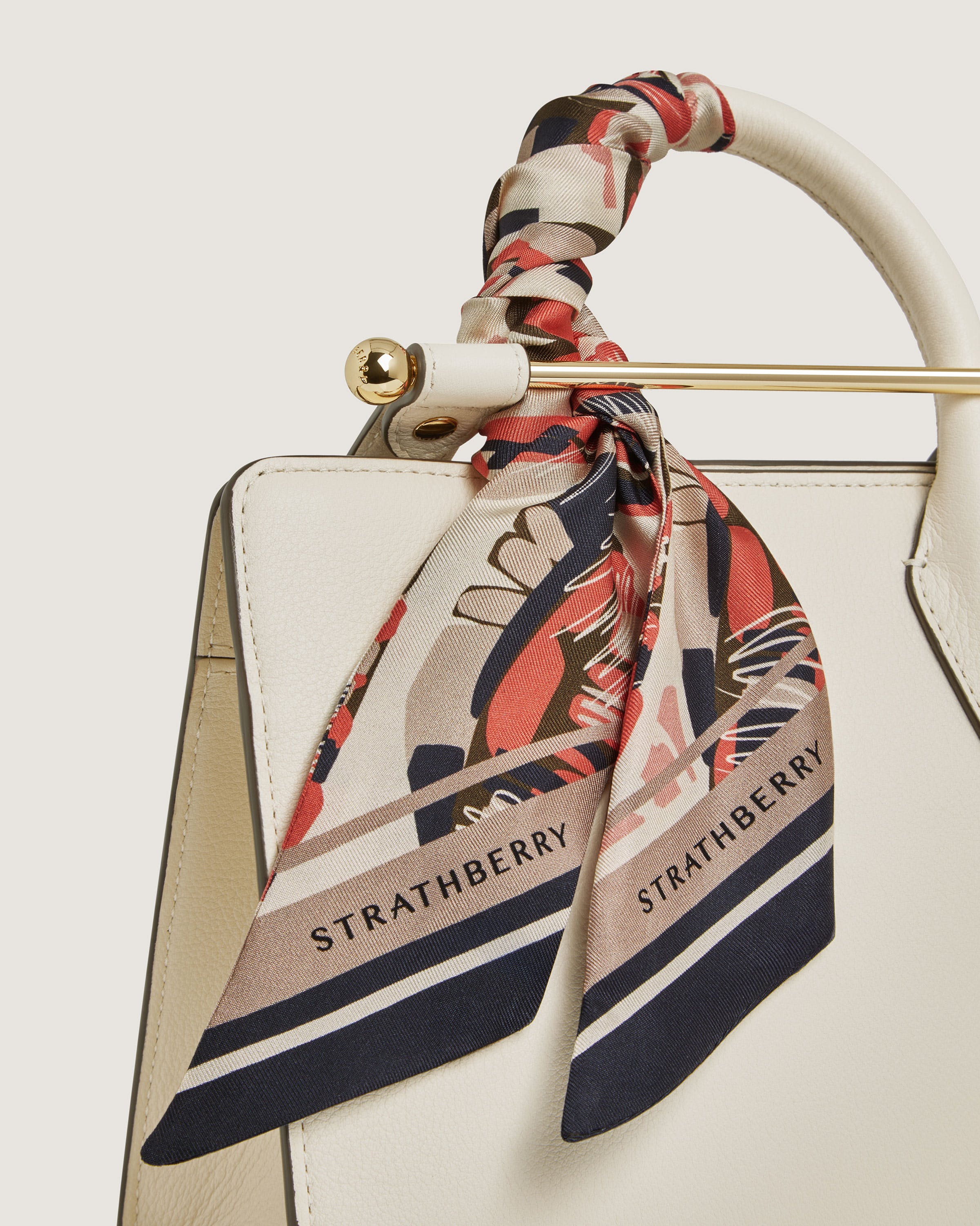 A white handbag with a red, white, and blue scarf tied around it