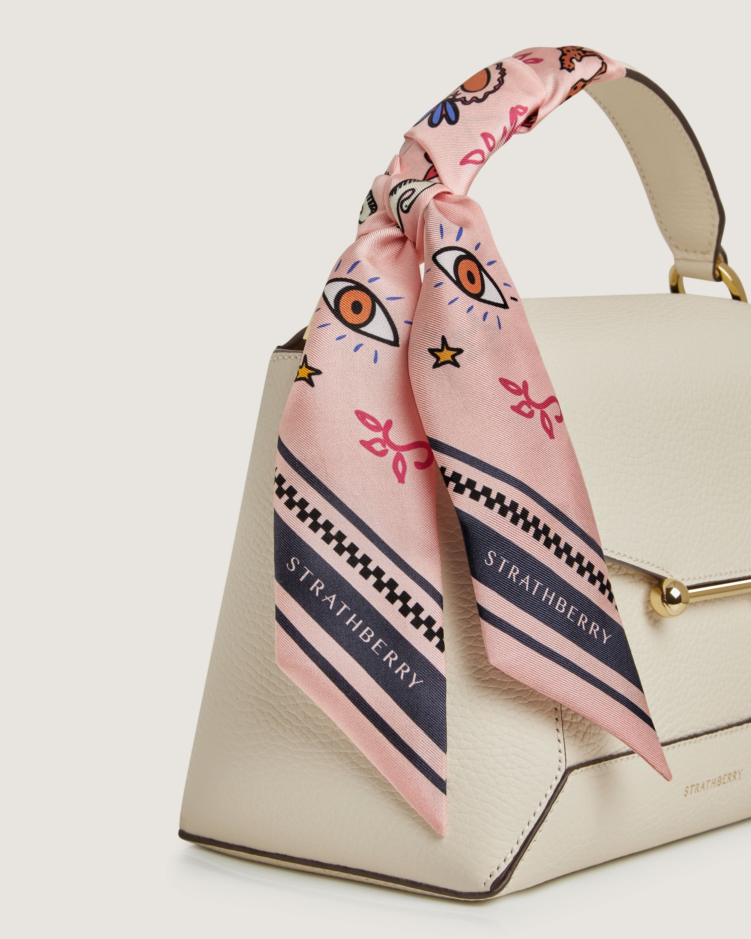 A white purse with a pink scarf tied around it