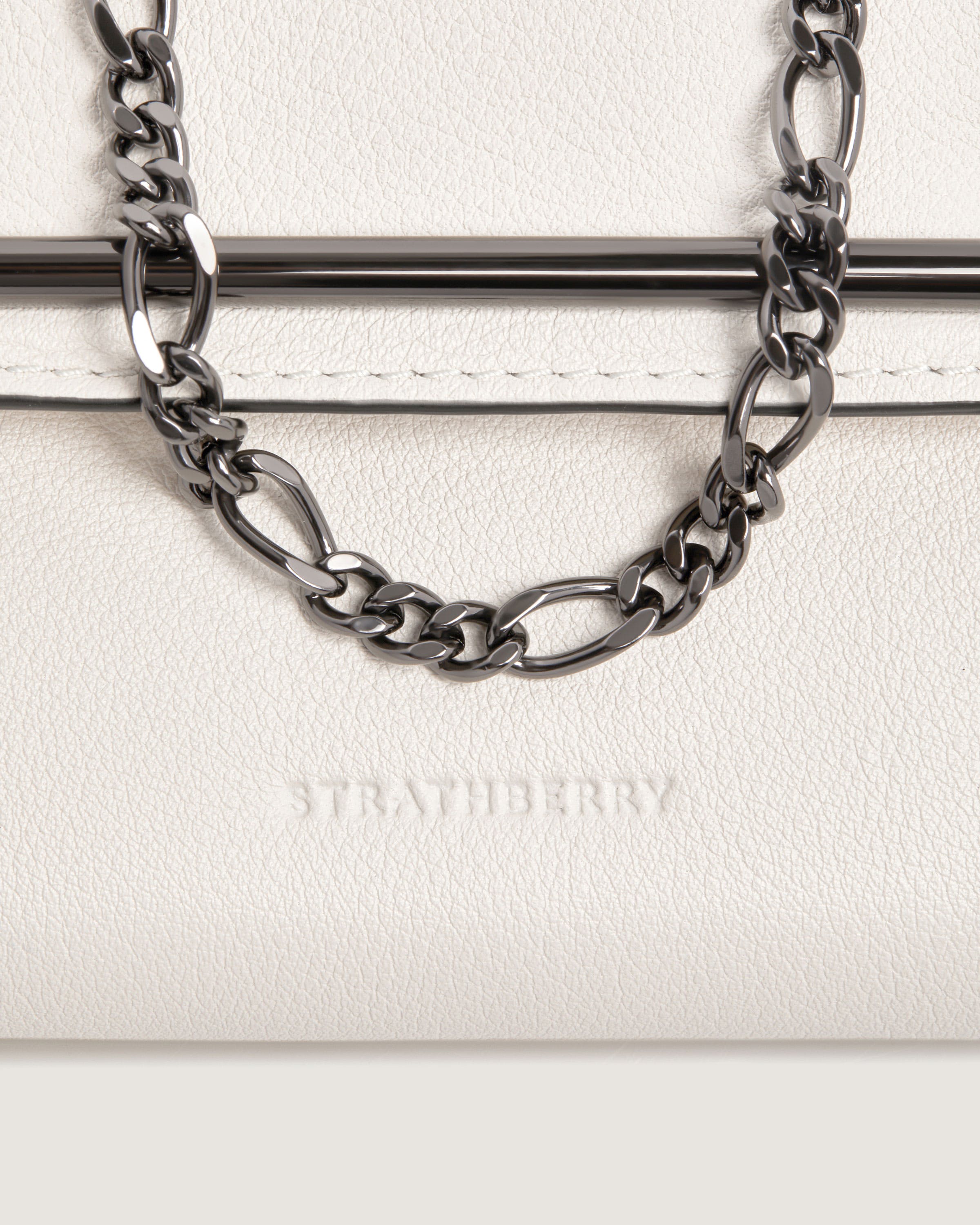 A white purse with a chain hanging from it