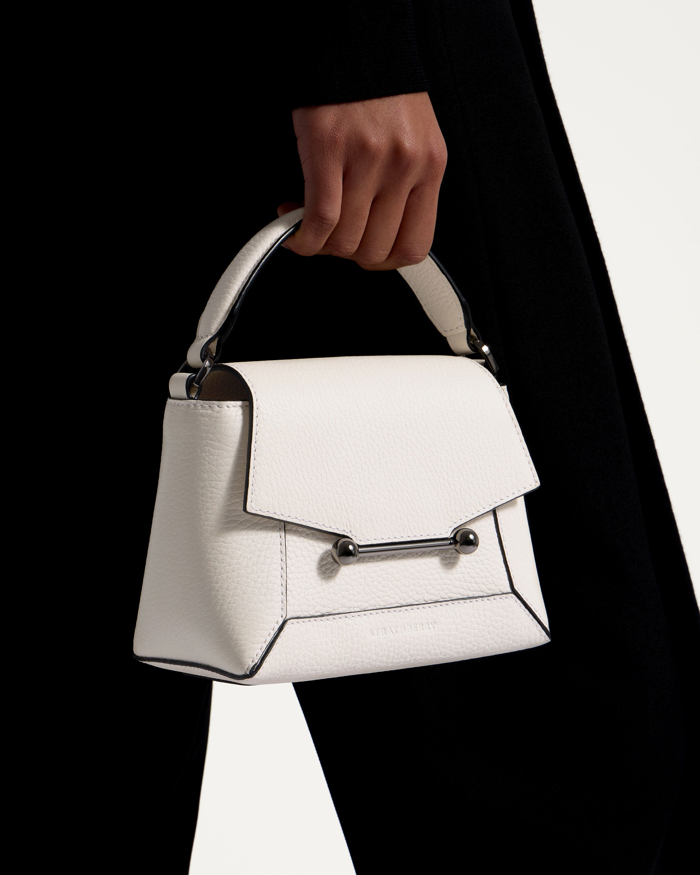 A person holding a white purse with a metal handle