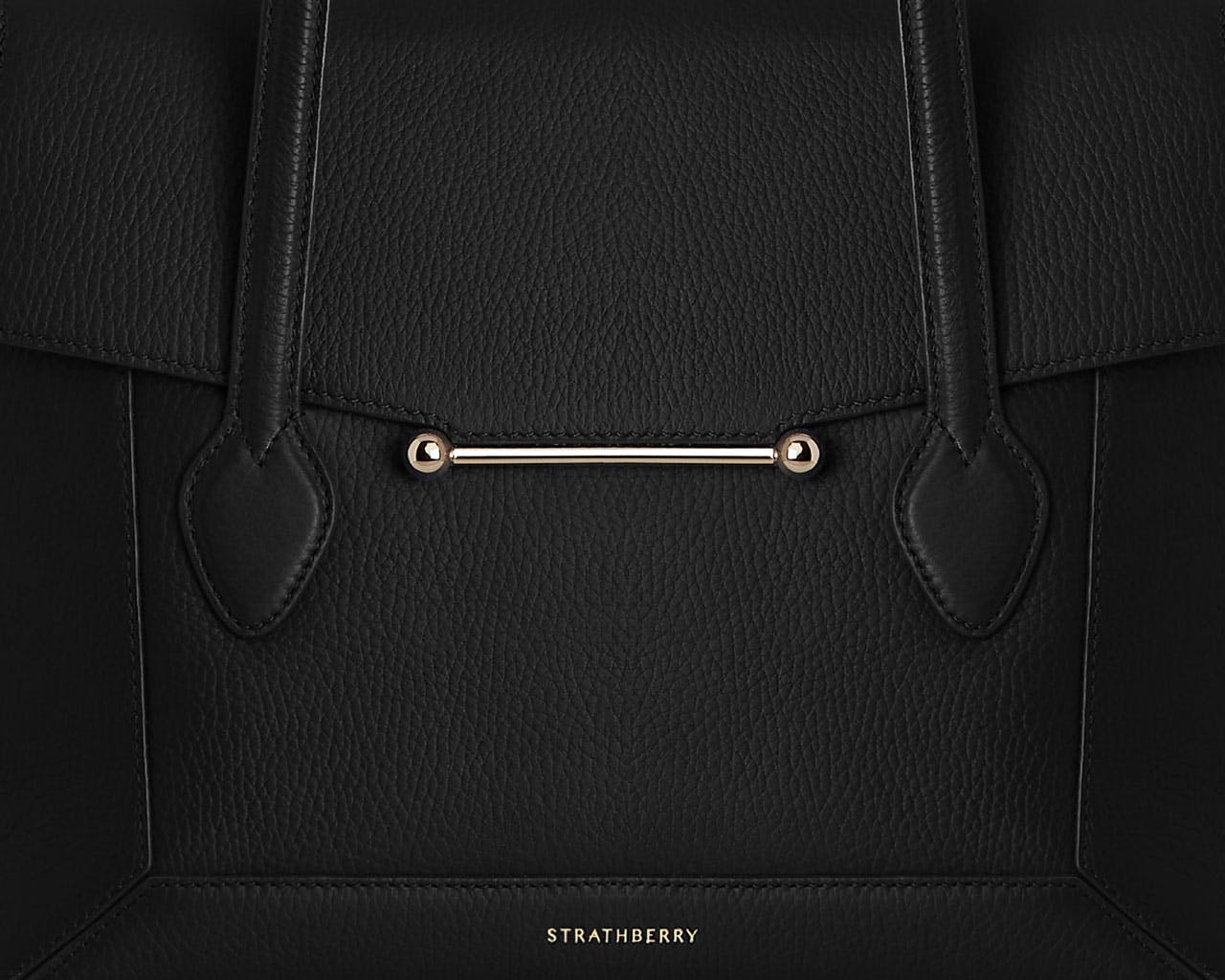 A black handbag with a gold handle