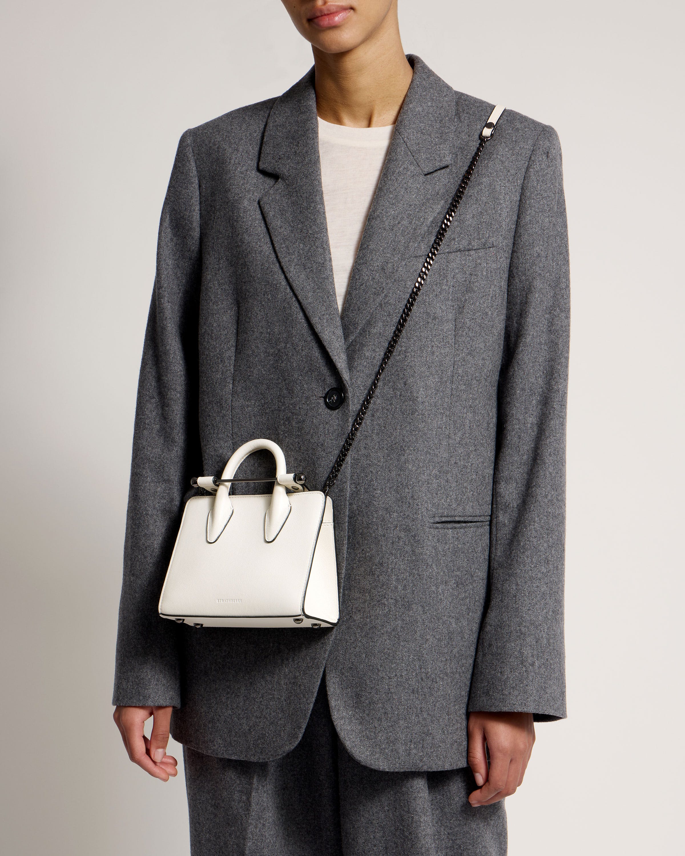 A woman in a gray suit holding a white purse