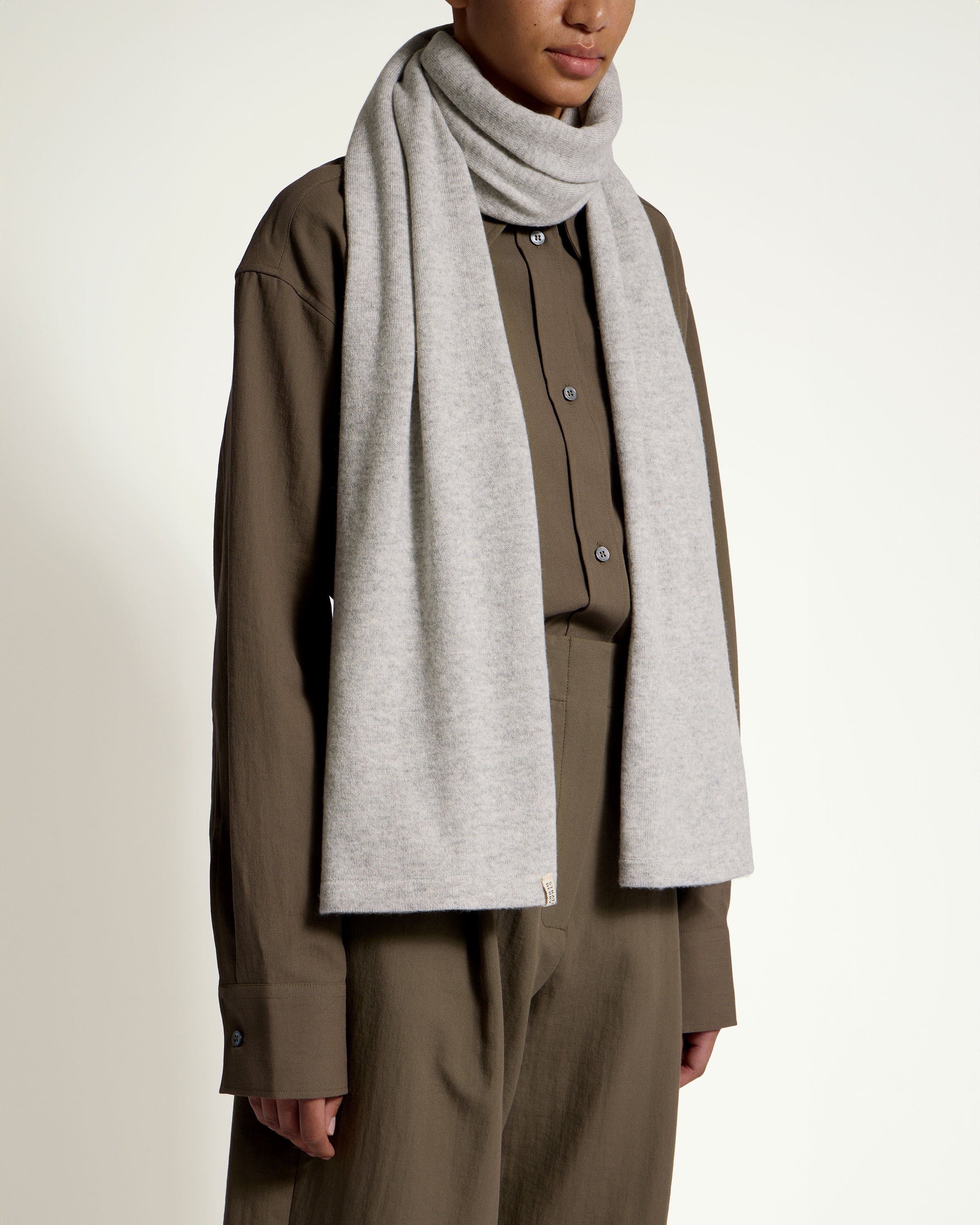 A woman wearing a gray scarf and brown pants