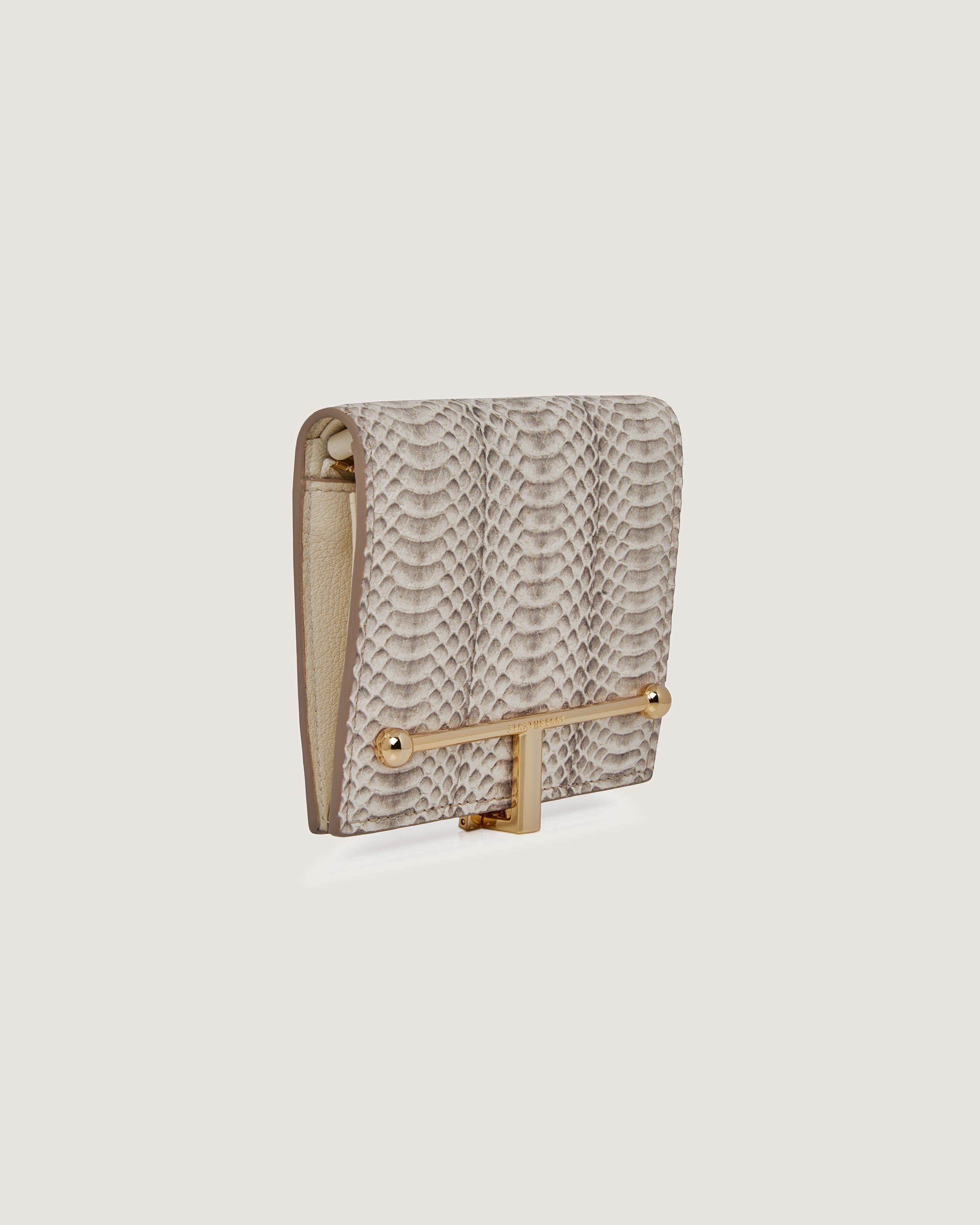 A white snake skin purse with a gold handle