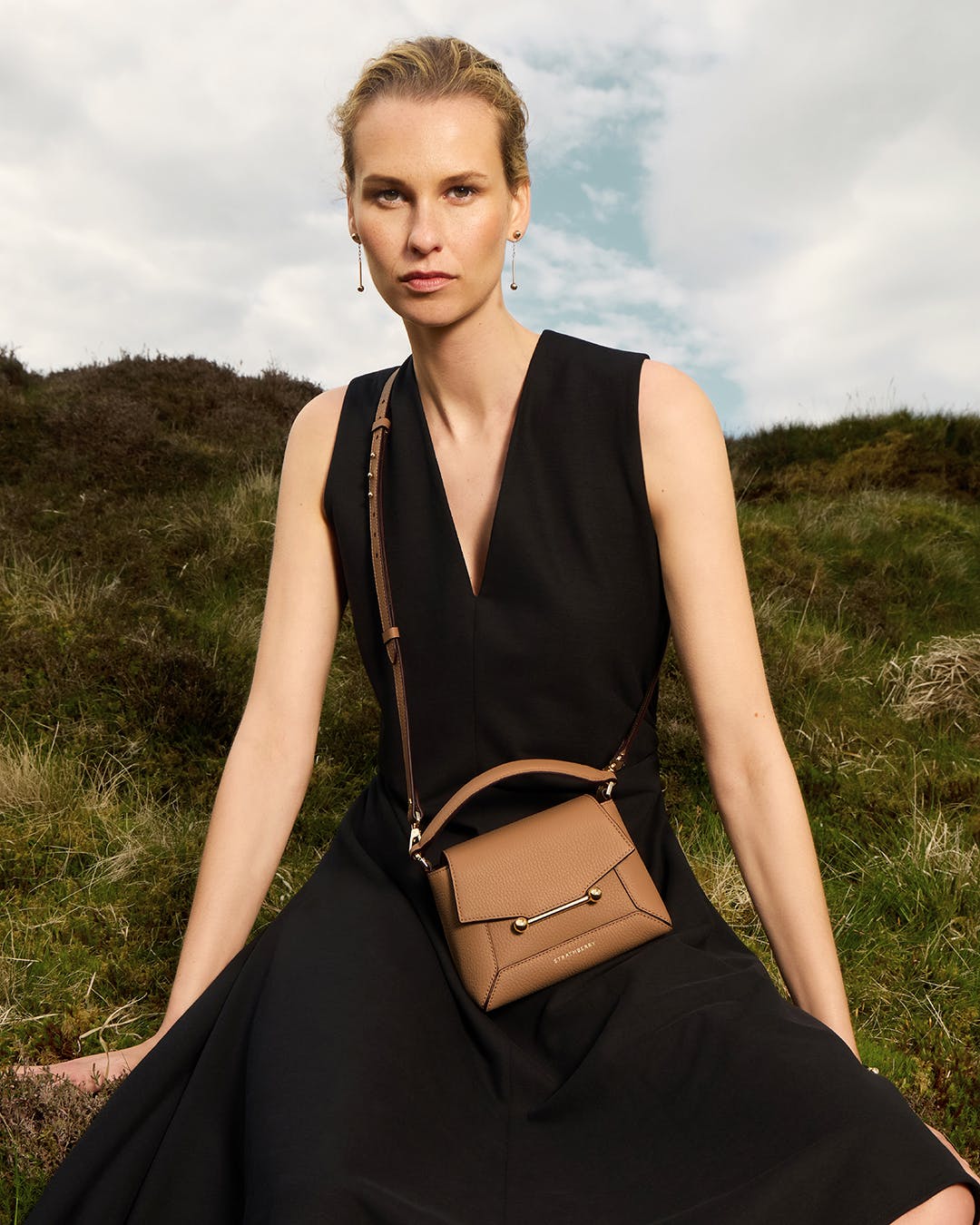 A woman in a black dress sitting on a hill