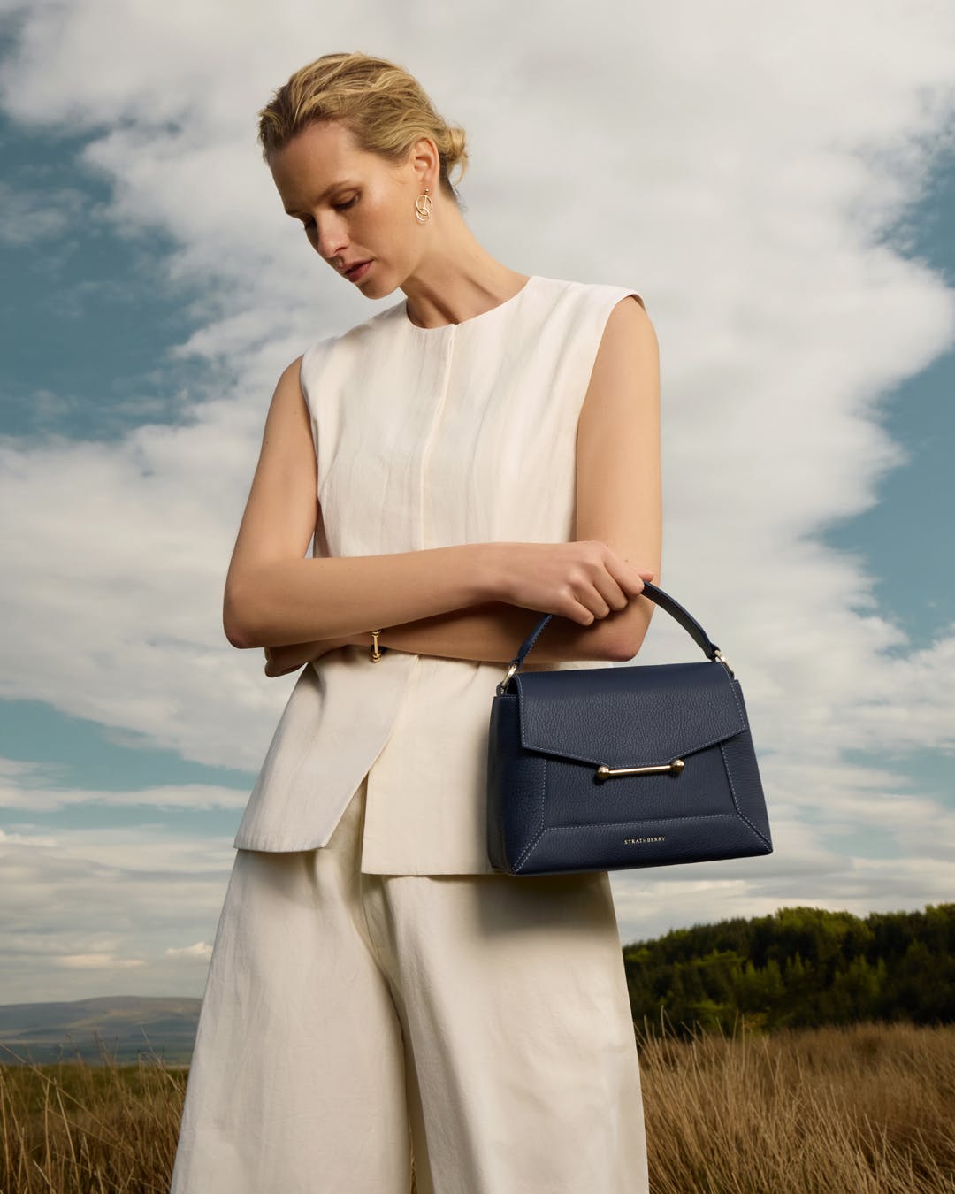 A woman in a white dress holding a blue handbag