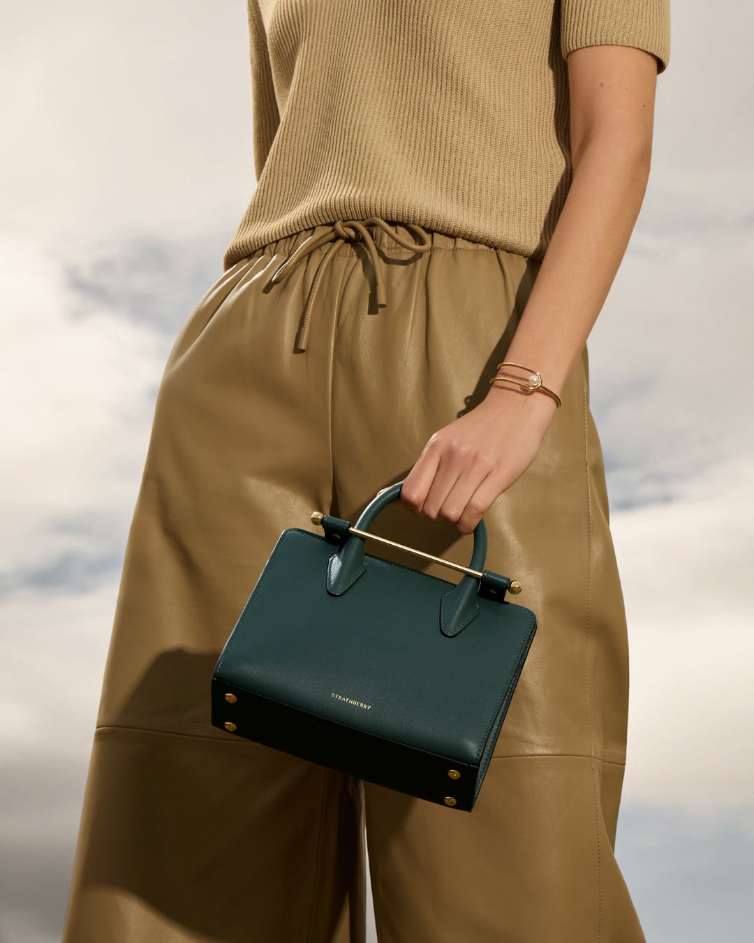 A woman holding a green handbag in her right hand