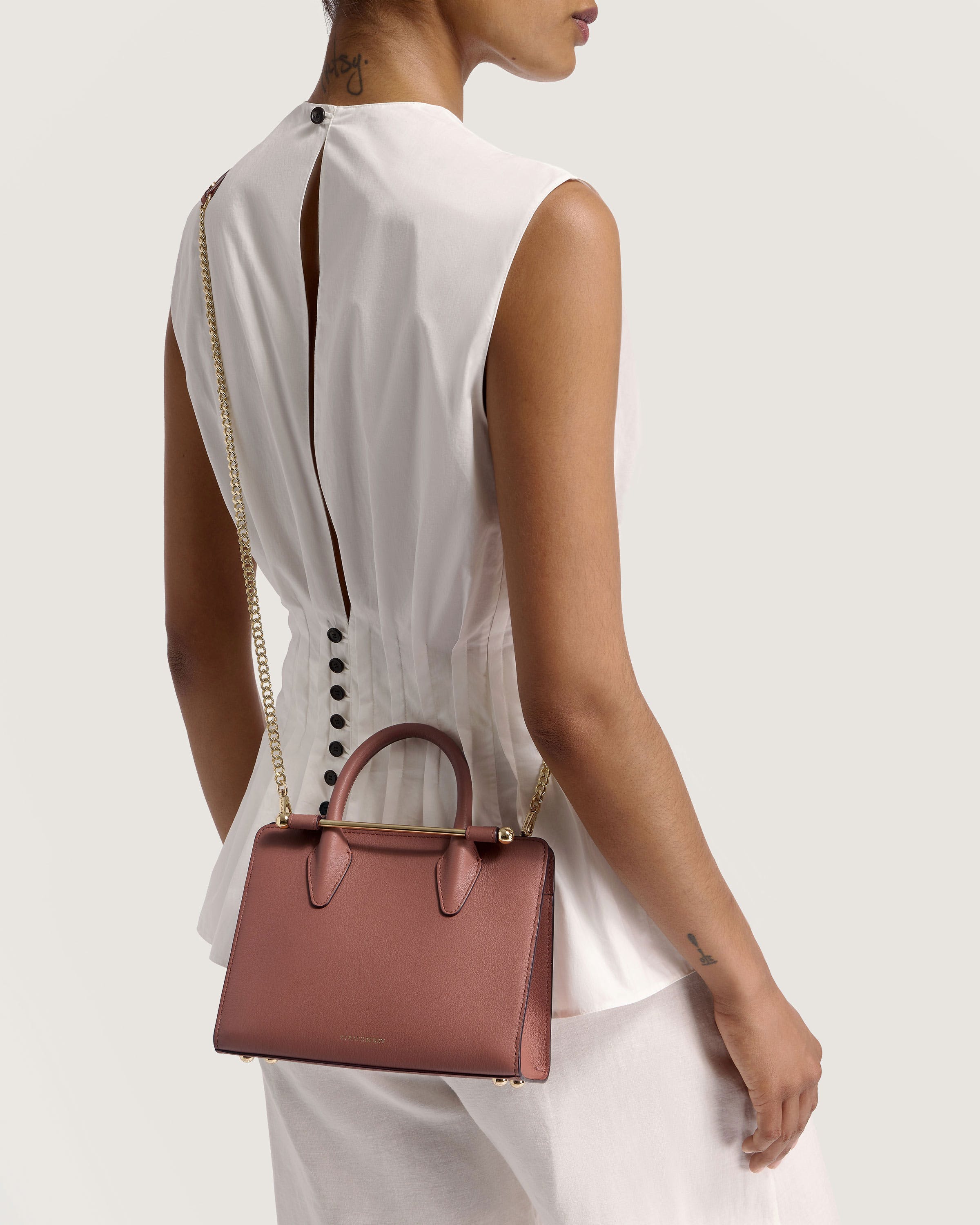 A woman in a white dress carrying a pink handbag