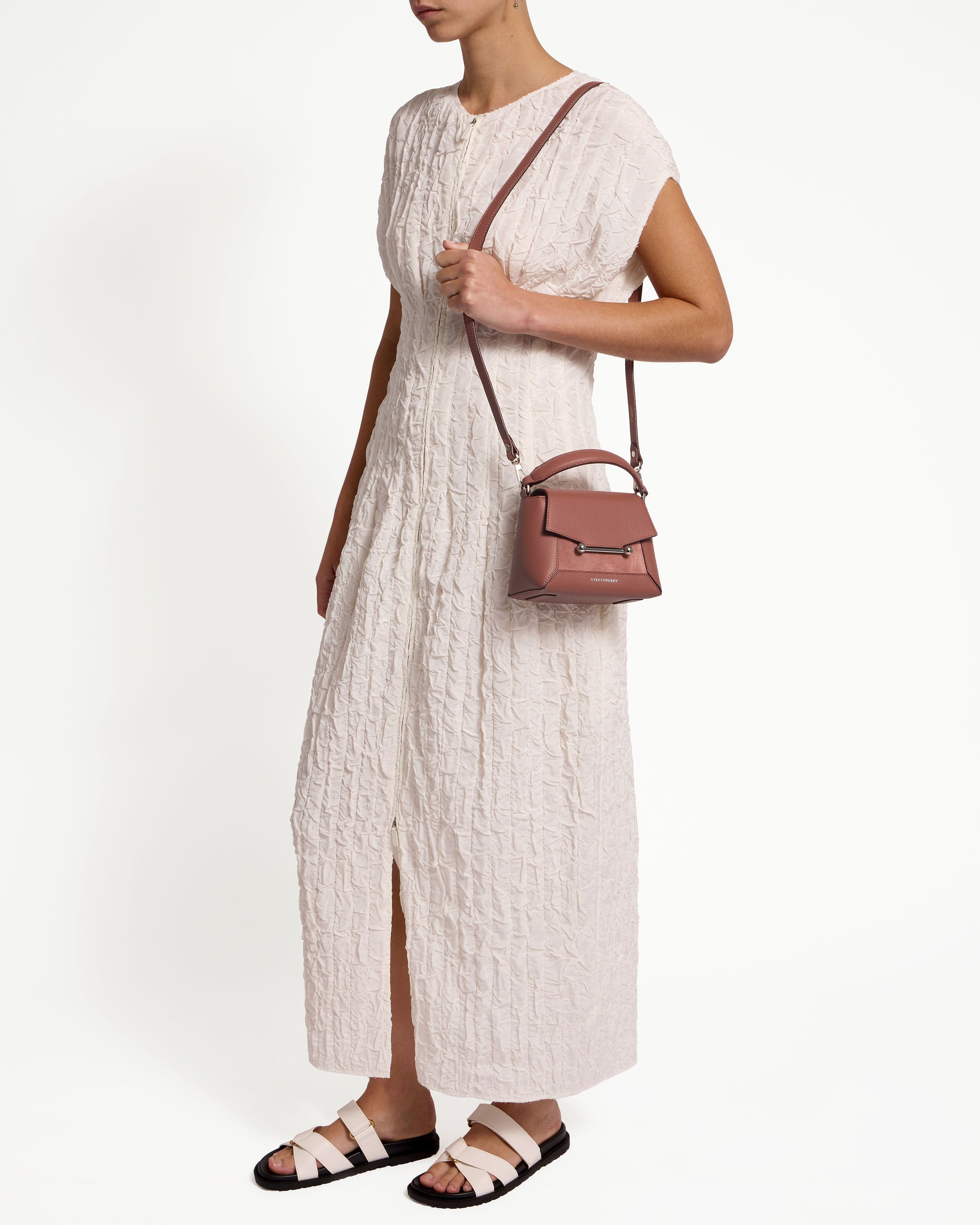 A woman in a white dress holding a brown purse