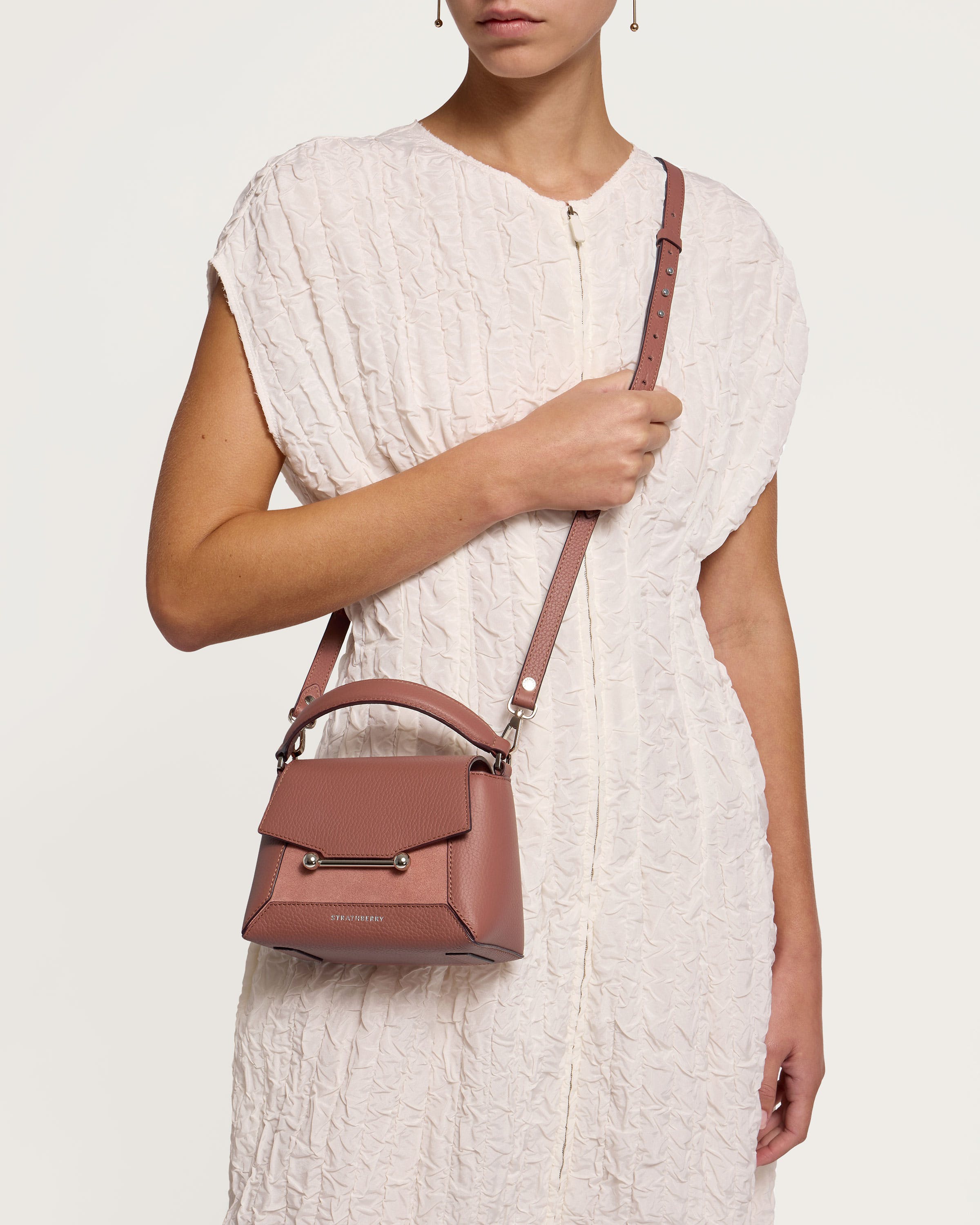 A woman in a white dress holding a brown purse