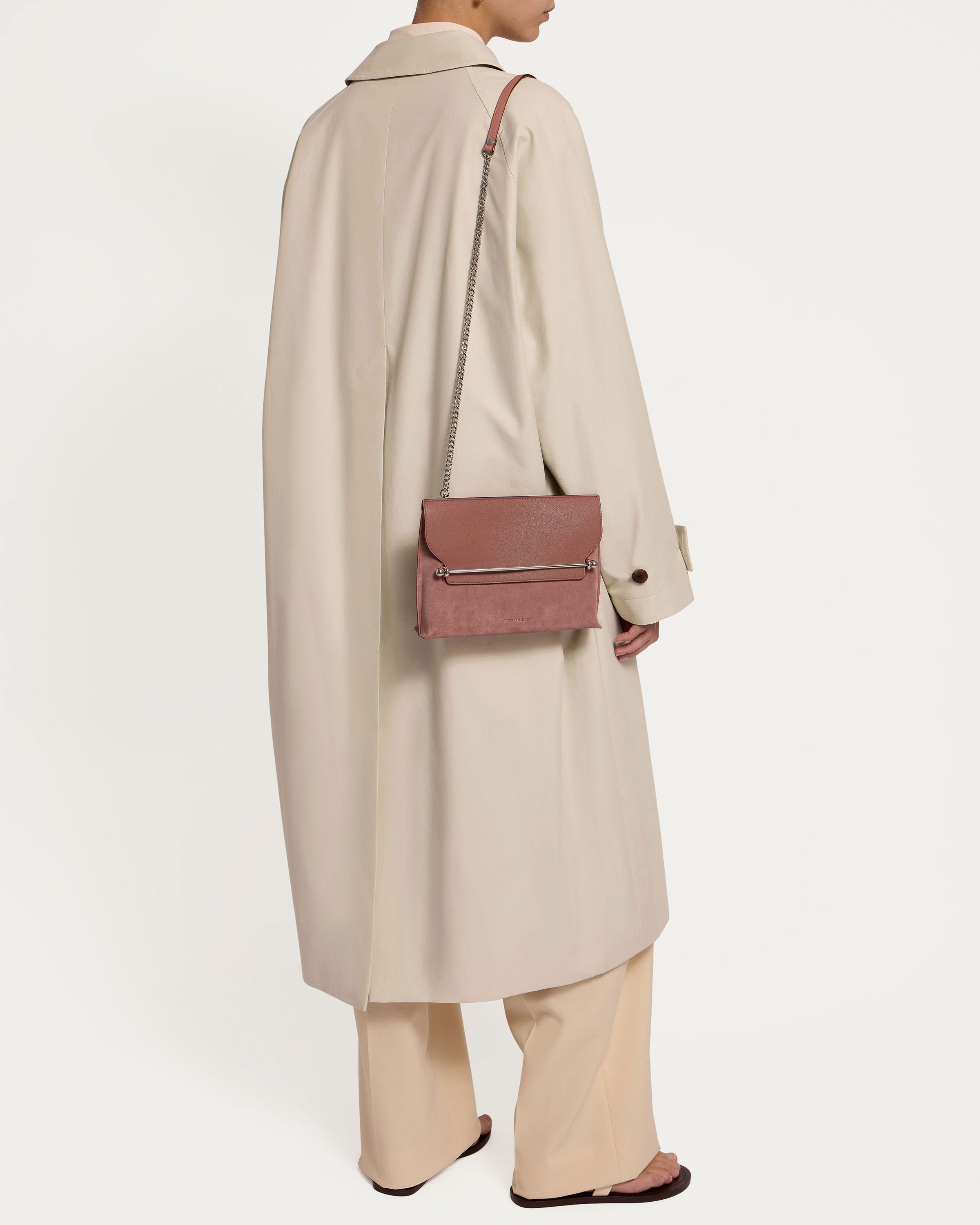 A woman wearing a beige coat and a pink purse