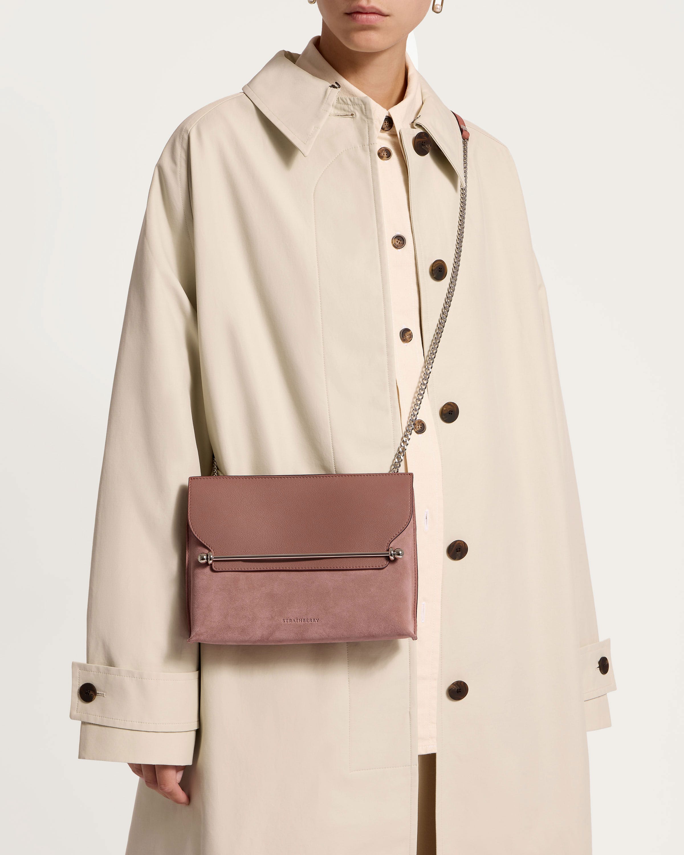 A woman in a trench coat holding a pink purse