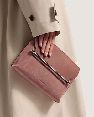 A woman in a trench coat holding a pink purse