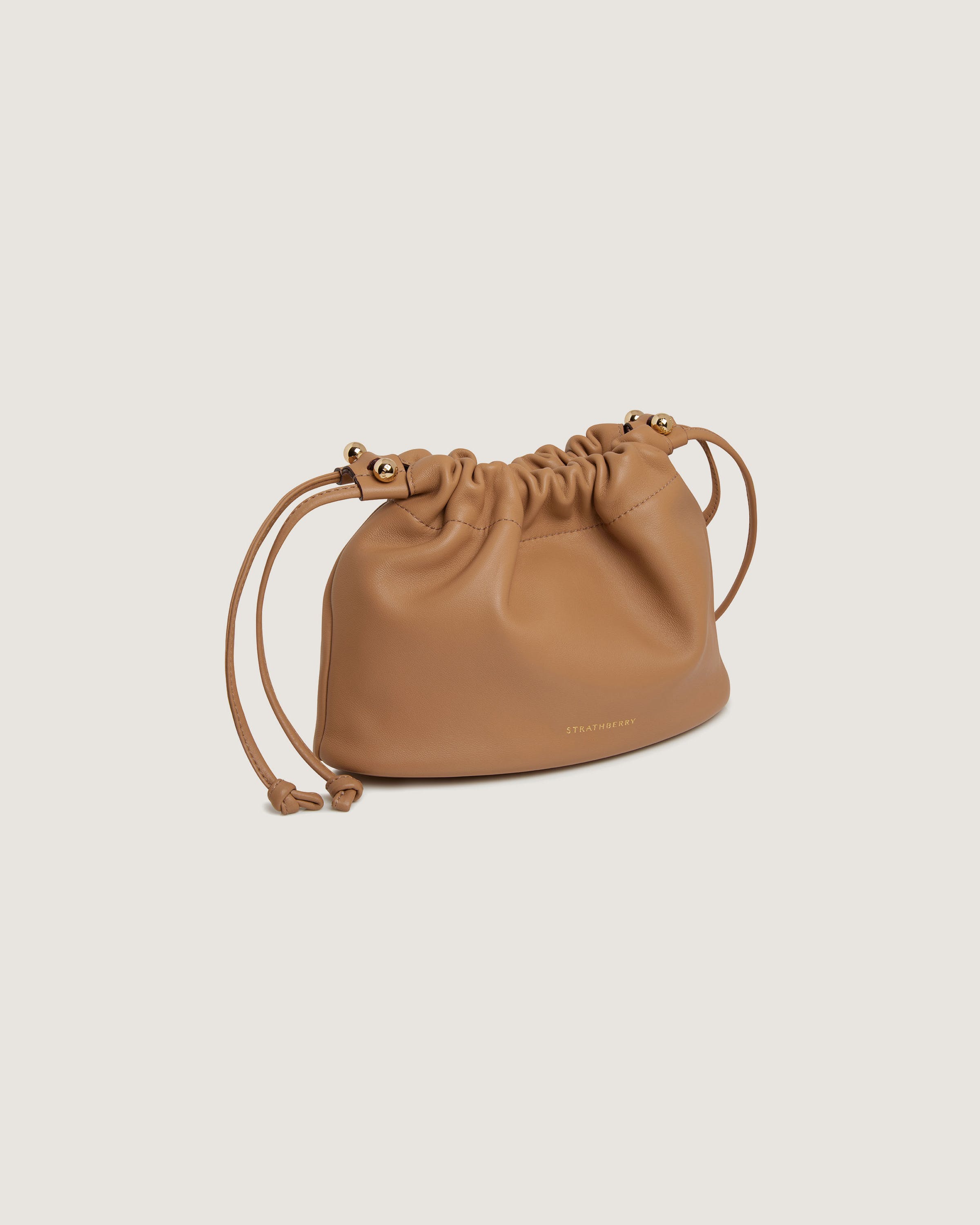 A tan leather bag with a drawstring strap