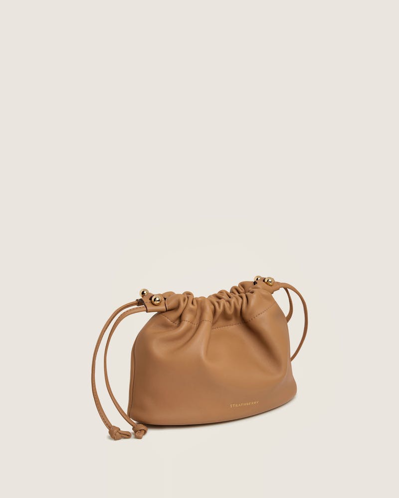 A tan leather bag with a drawstring strap