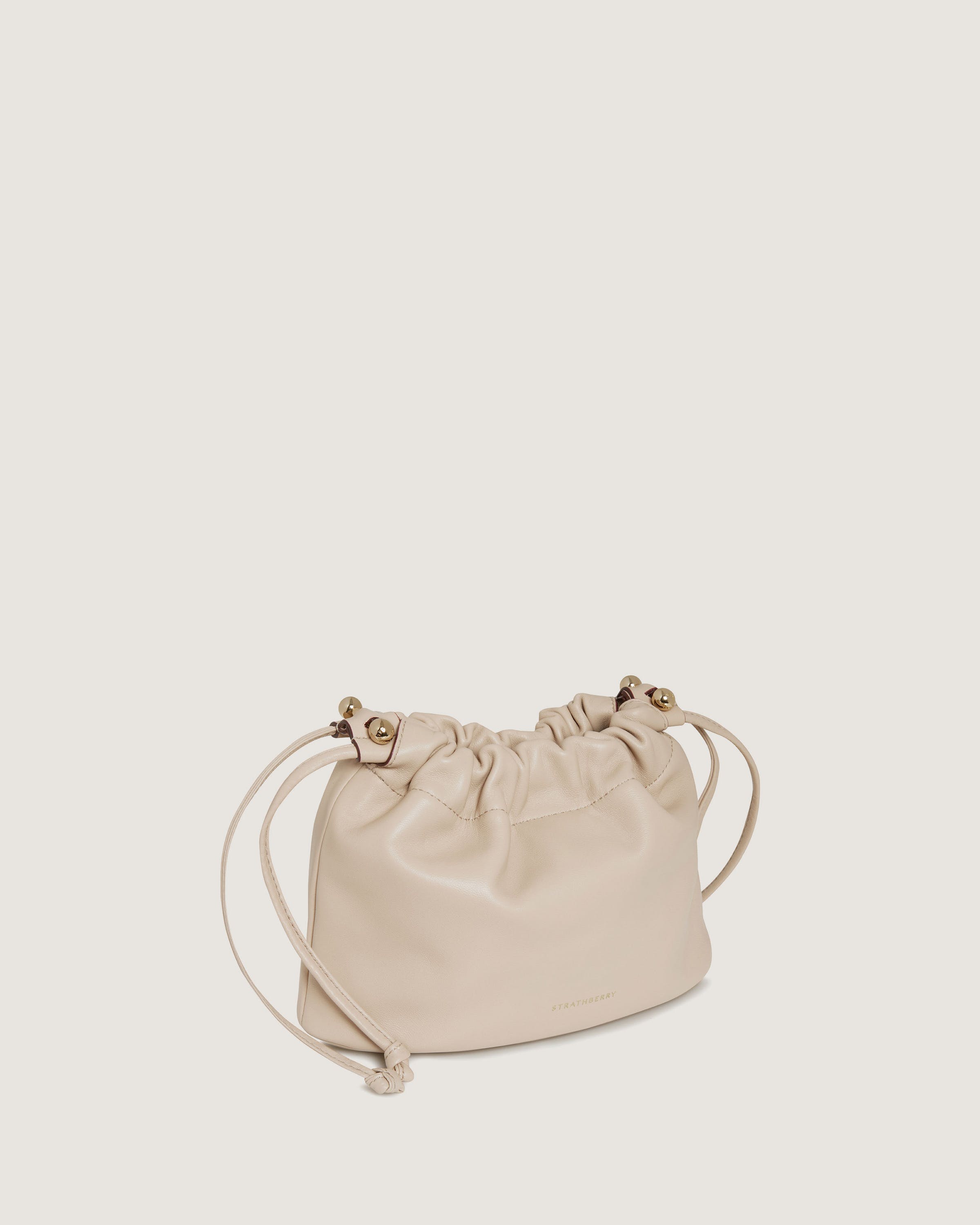 A beige leather bag with a drawstring strap