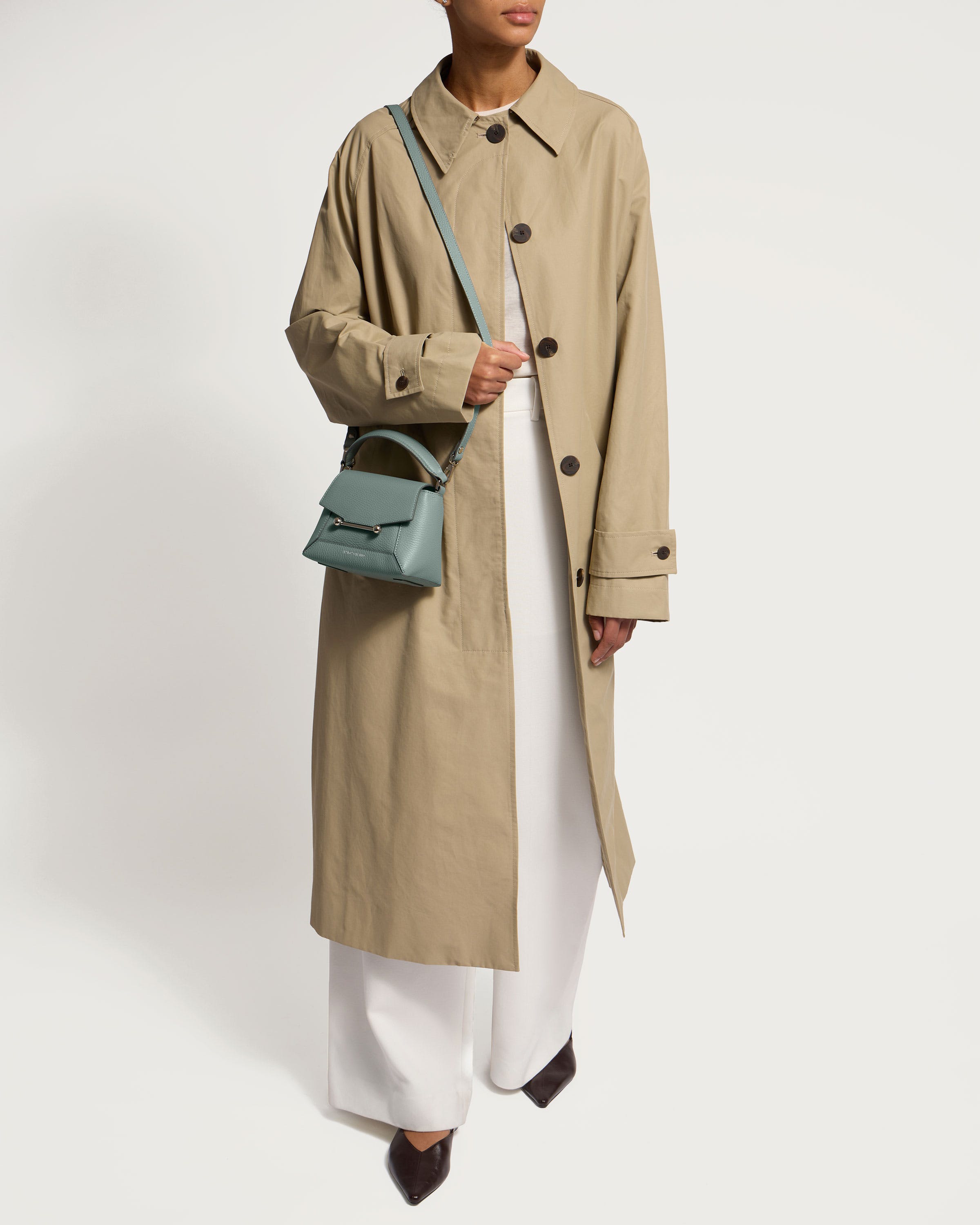 A woman wearing a trench coat and white pants