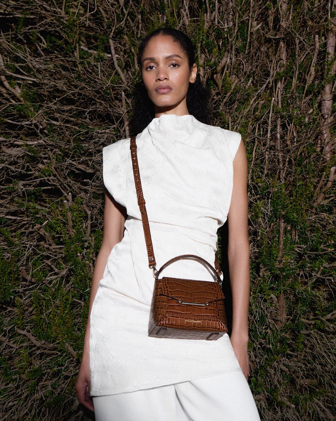 A woman in a white dress holding a brown purse