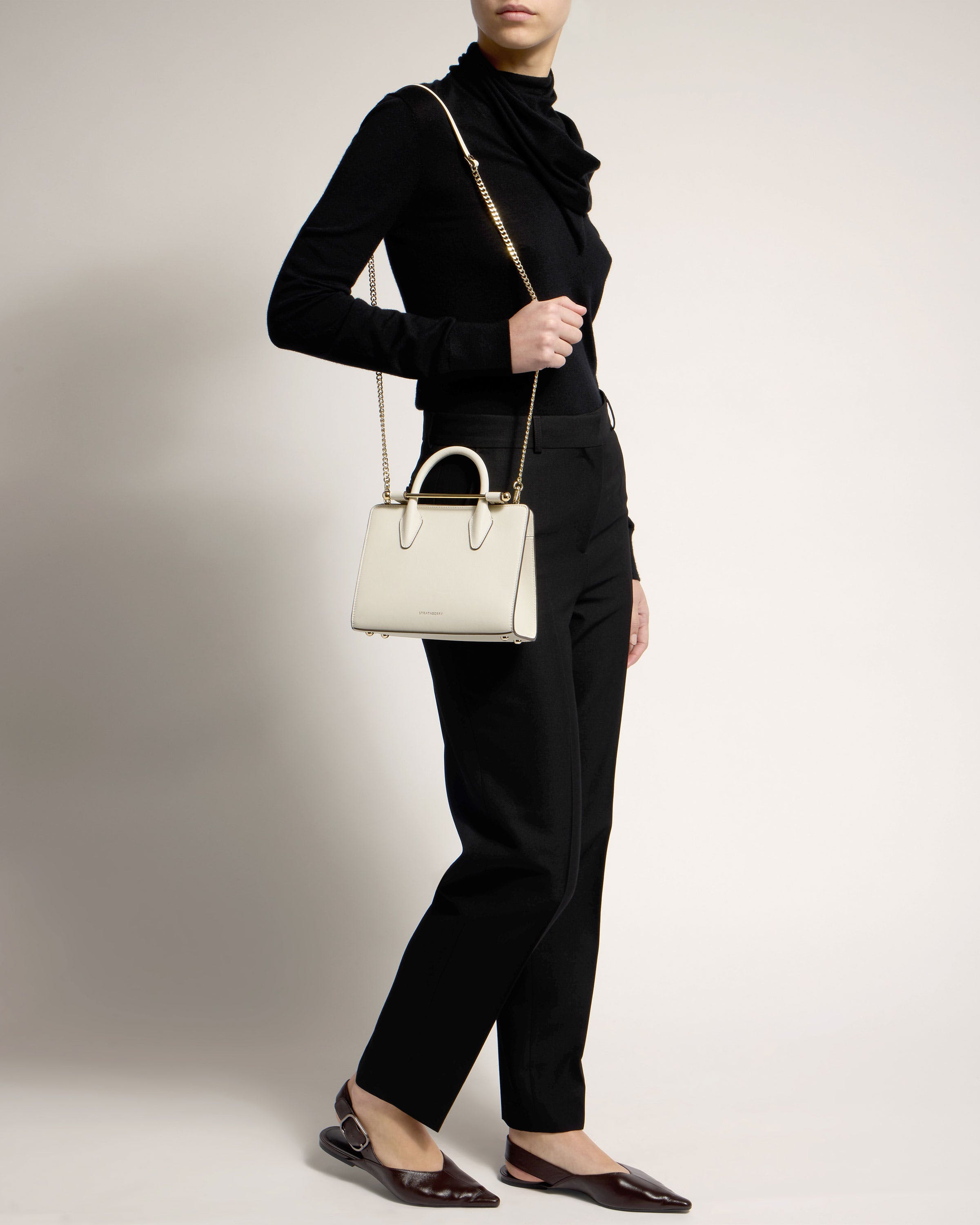 A woman is holding a white handbag