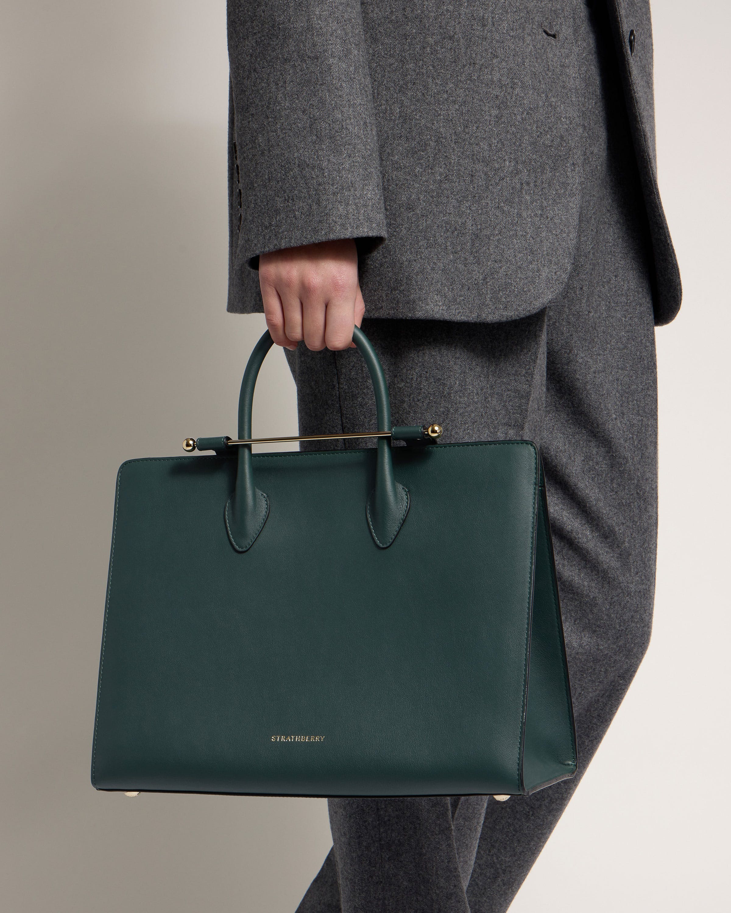 A person in a suit holding a green bag