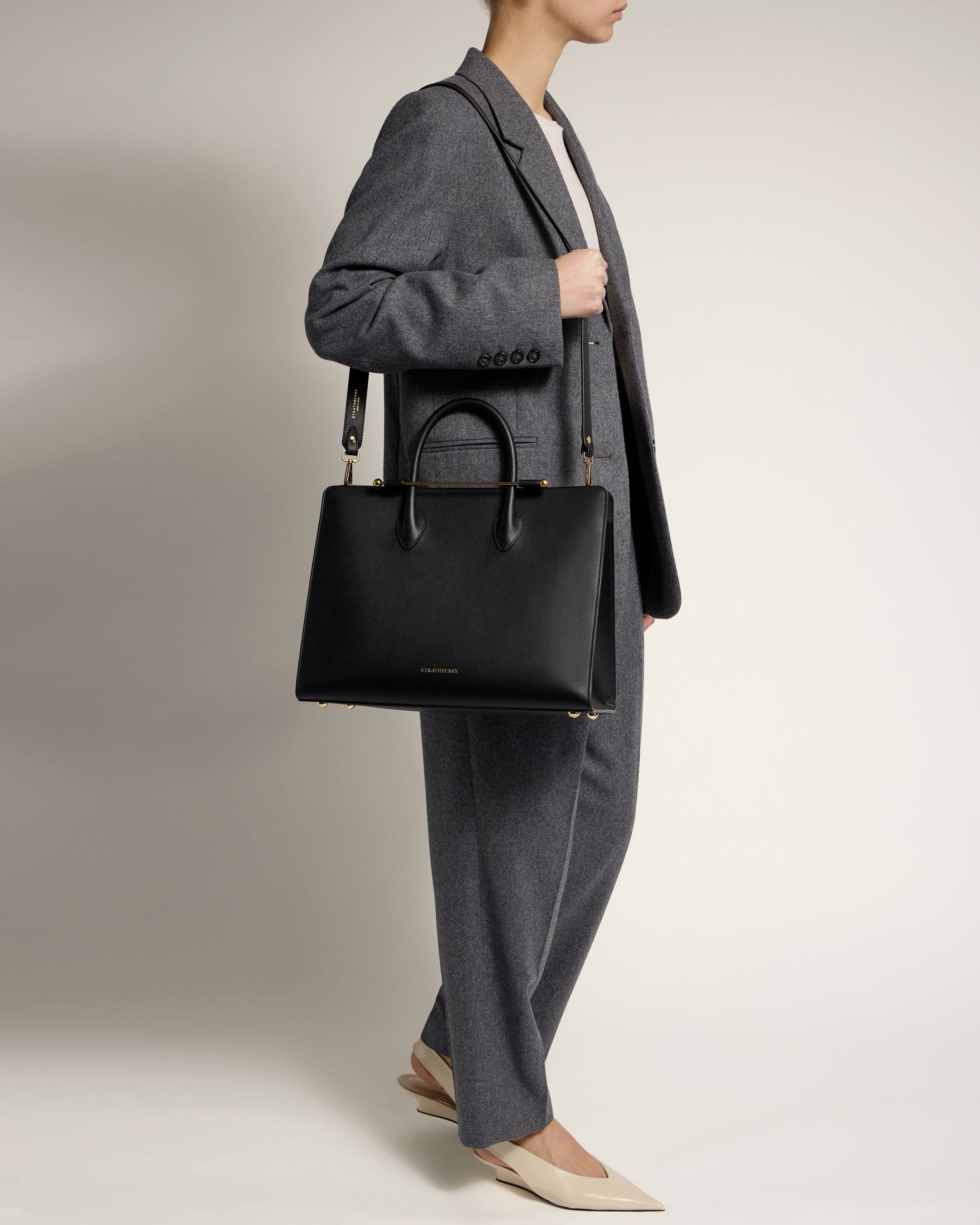 A woman holding a black handbag in her right hand