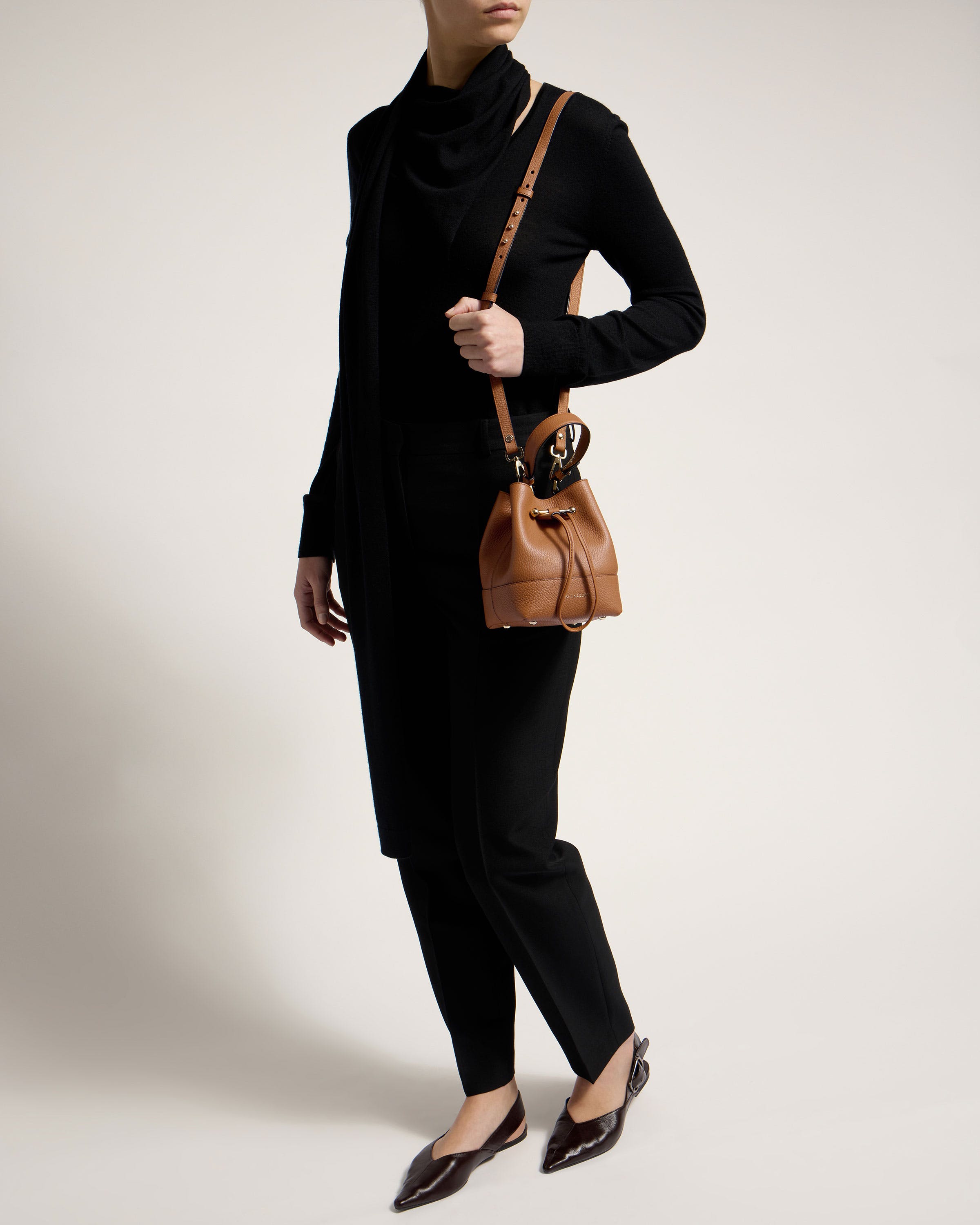 A woman in a black outfit holding a brown purse