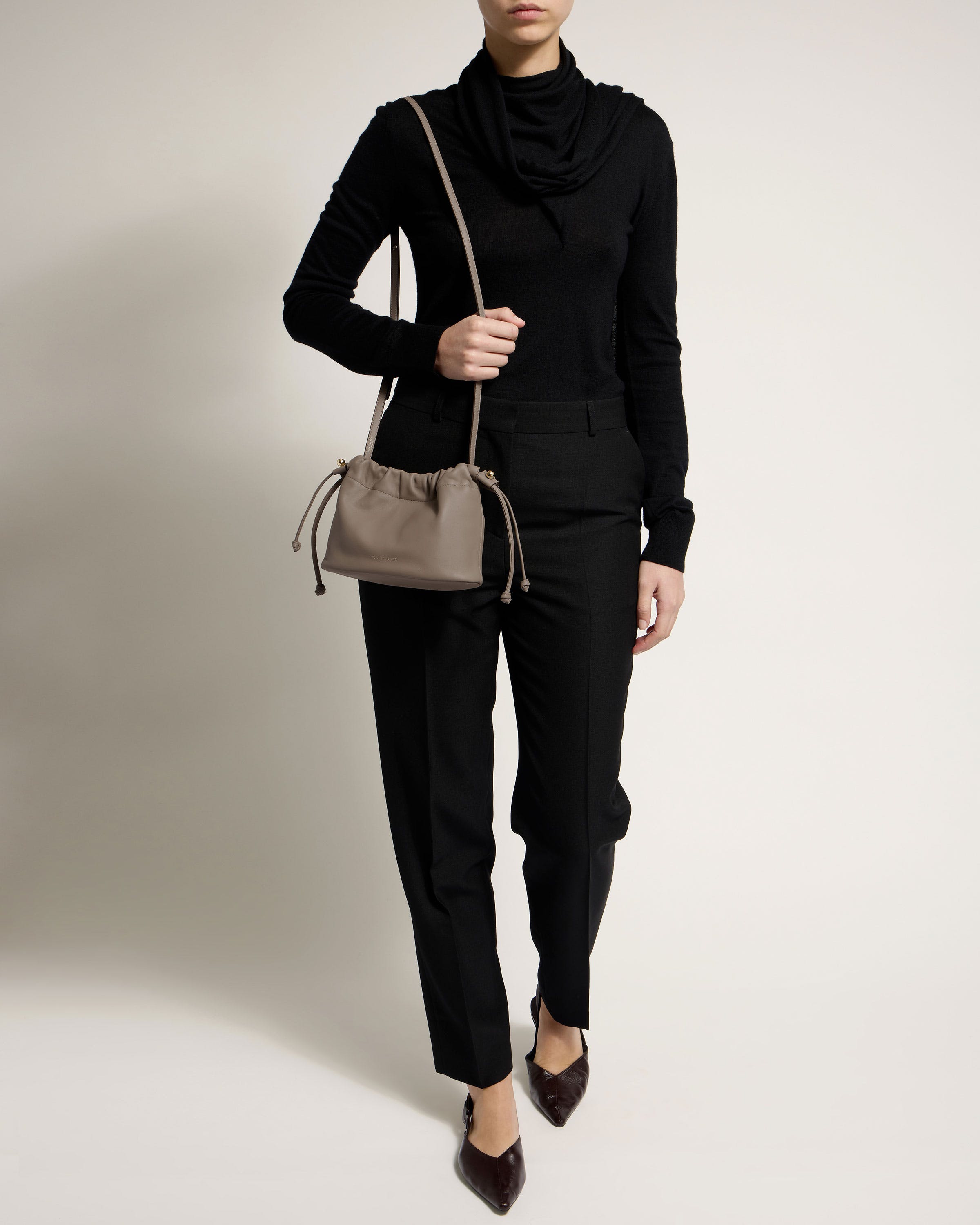 A woman in a black outfit holding a purse