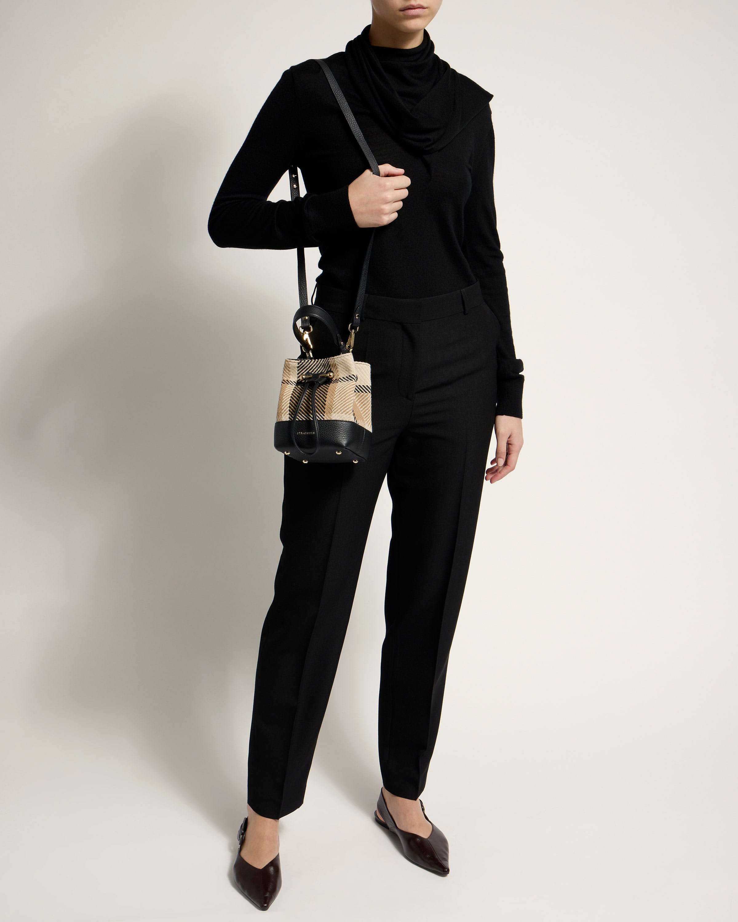 A woman in a black outfit holding a handbag