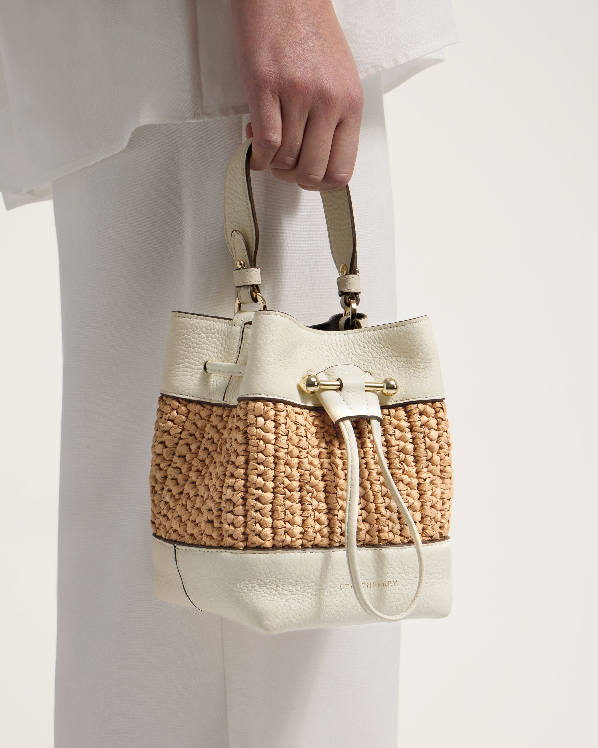 A person holding a white and tan purse