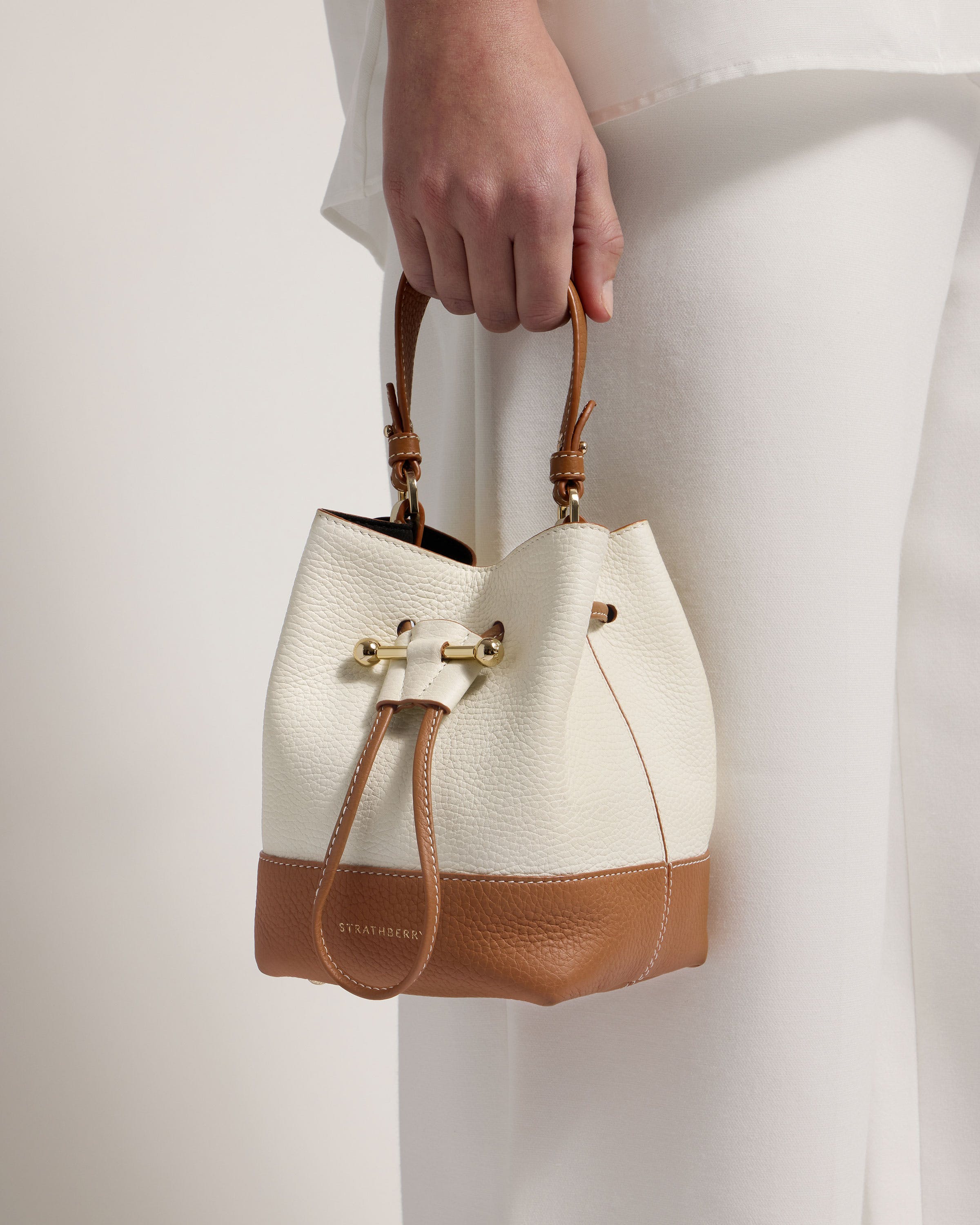 A woman holding a white and brown purse