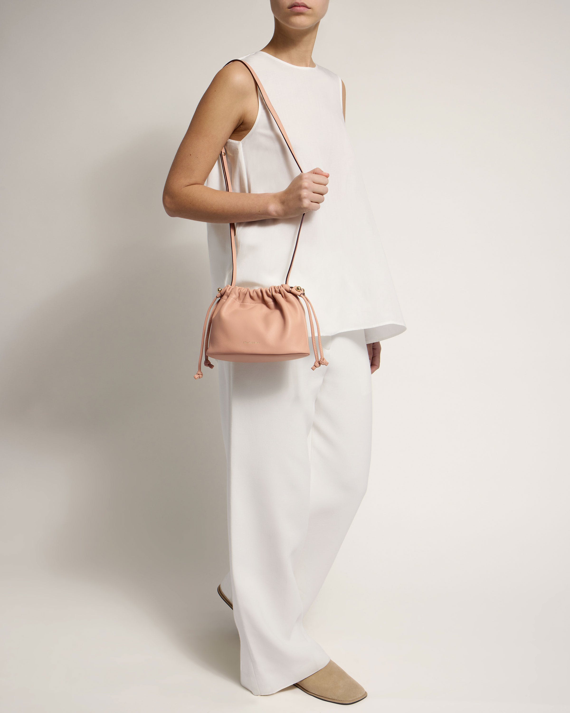 A woman in white holding a pink purse