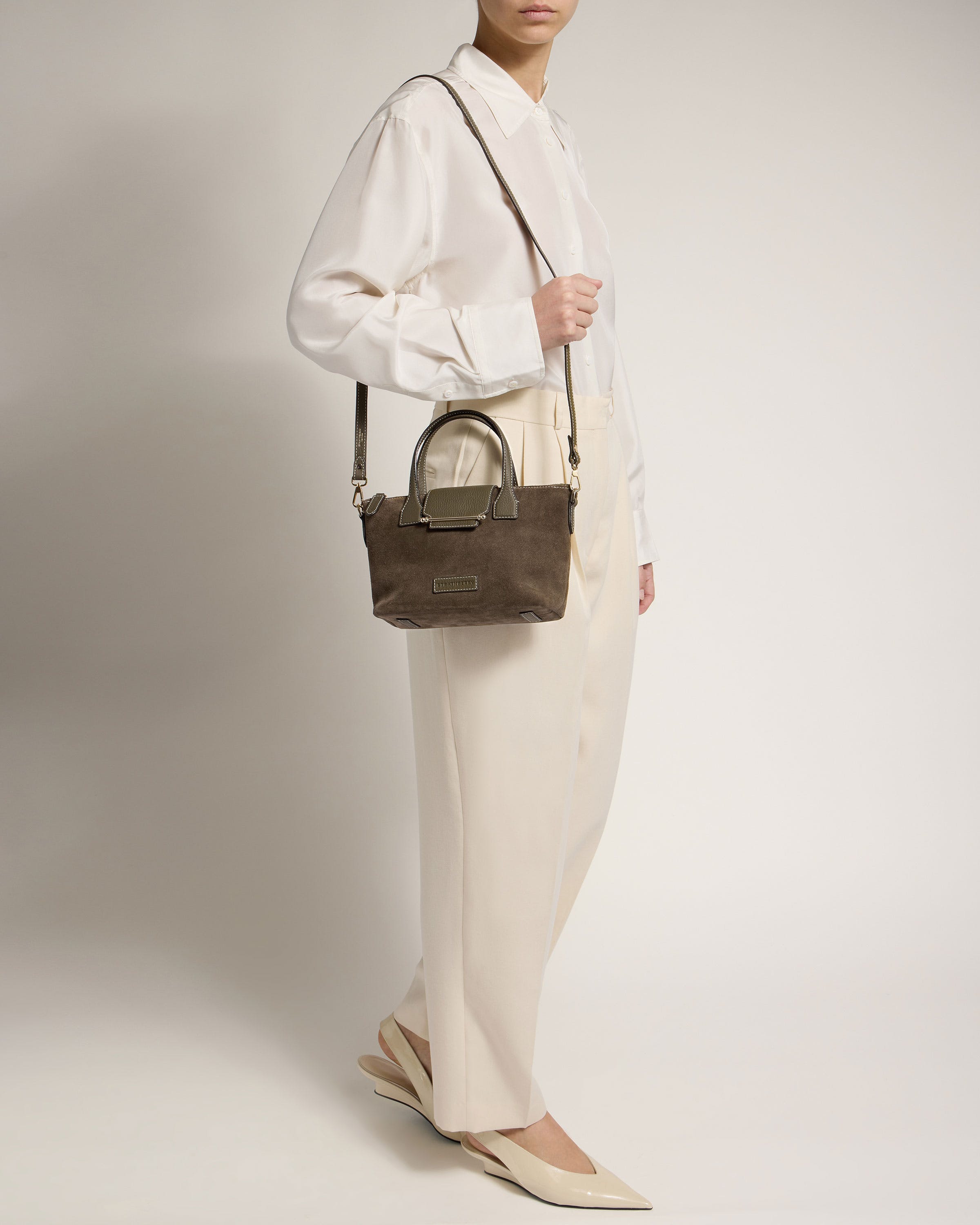 A woman is holding a brown handbag