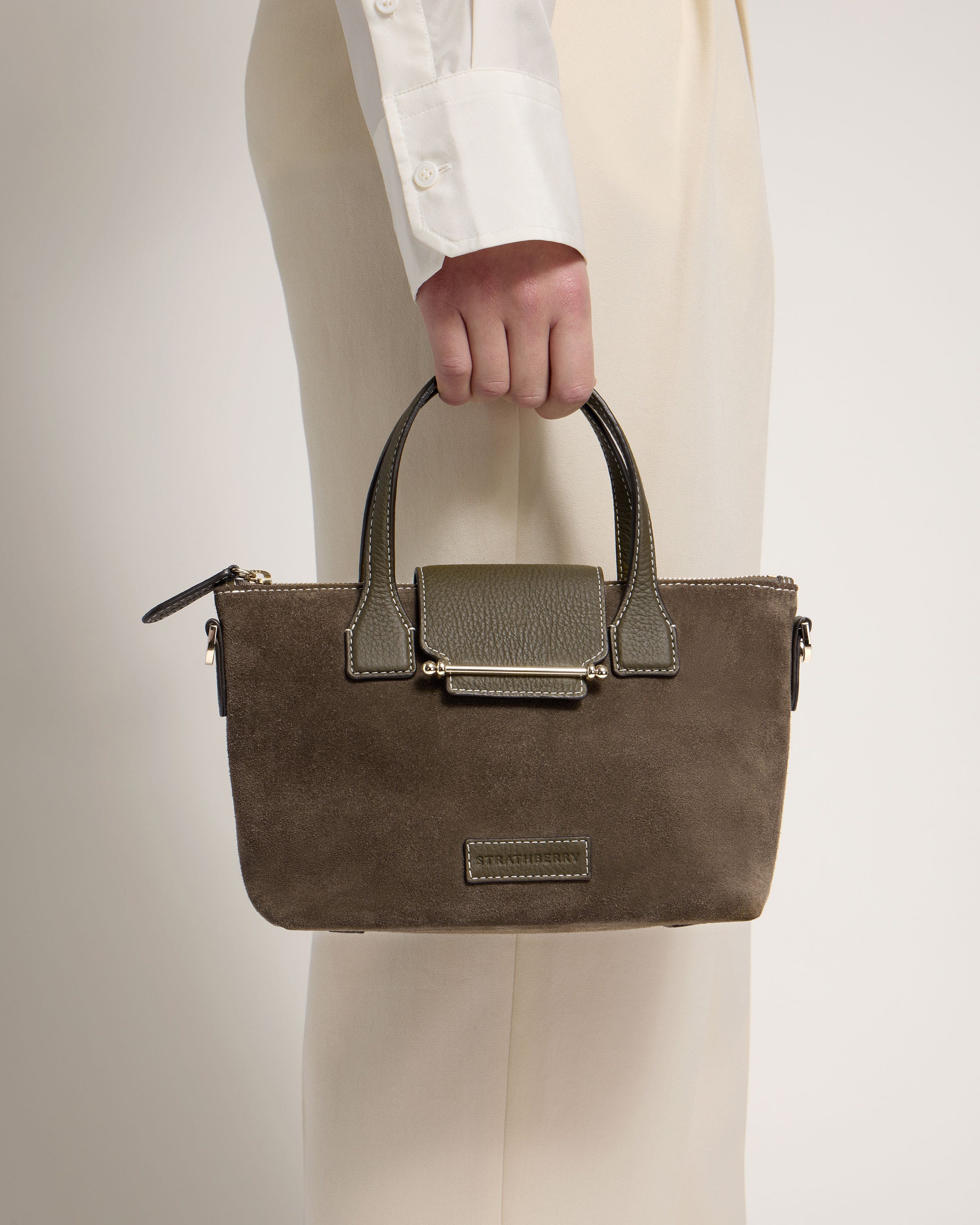 A person holding a brown purse with a white shirt