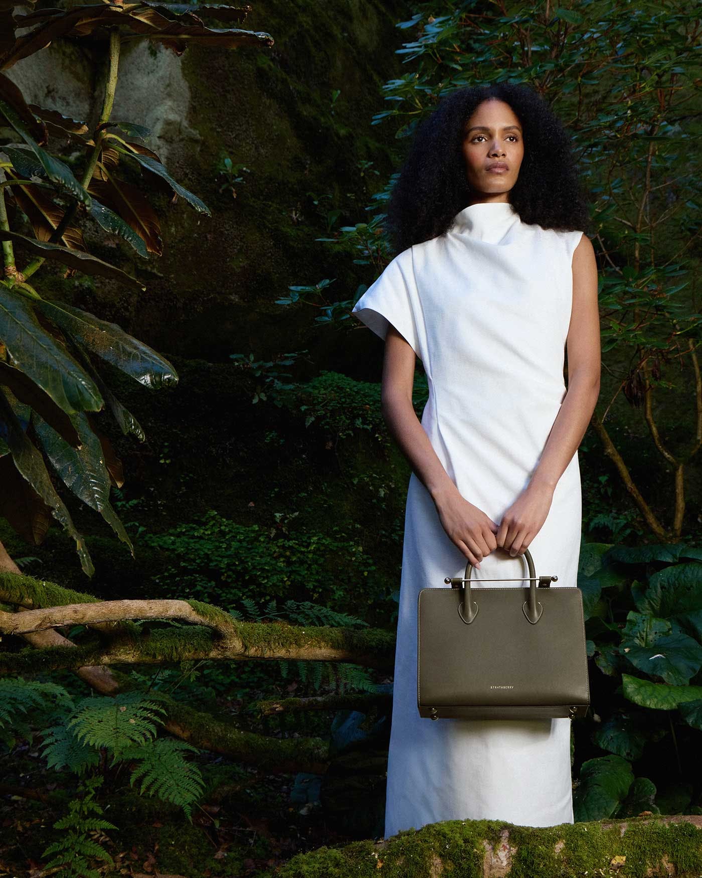 A woman in a white dress holding a brown purse