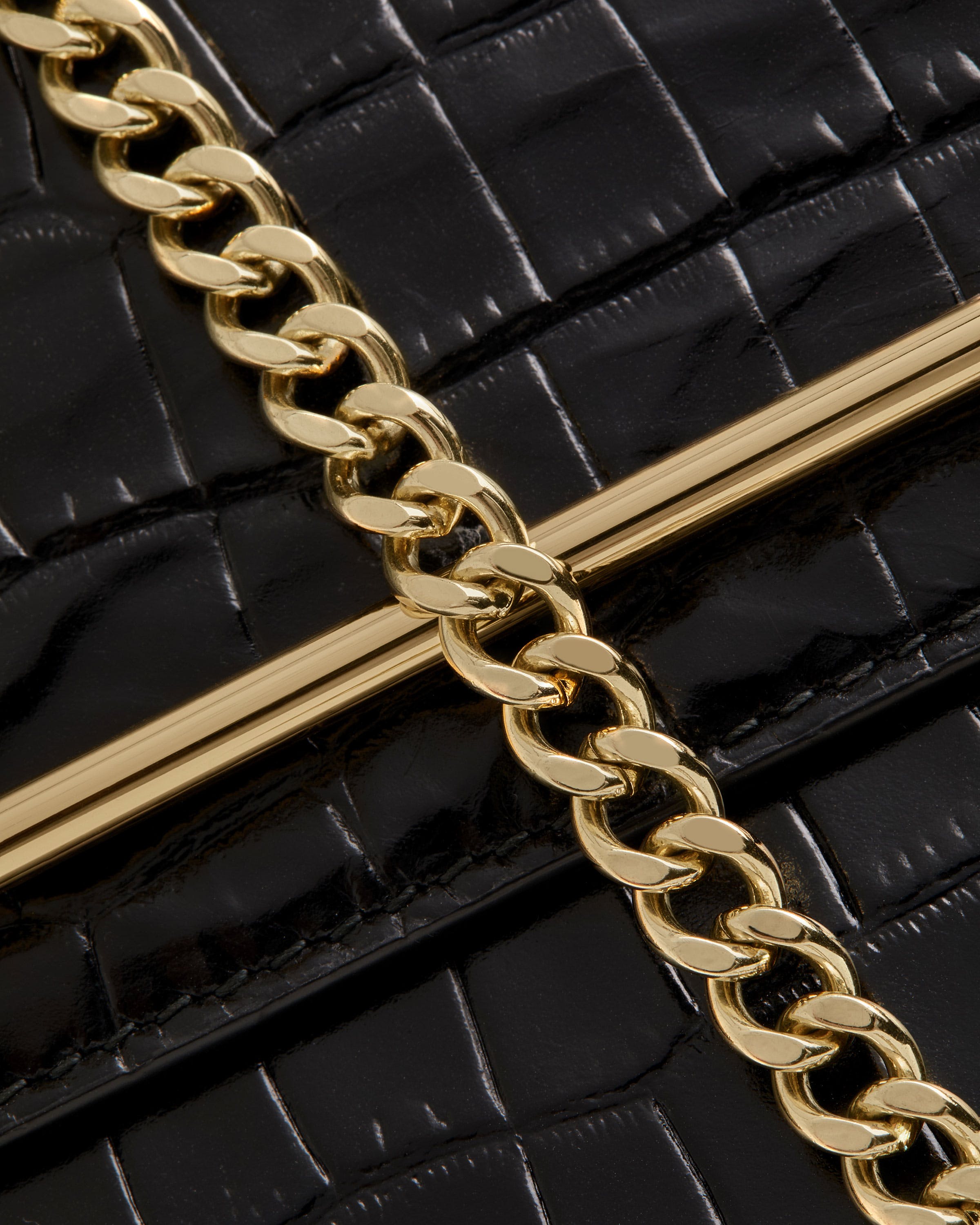 A close up of a gold chain on a black purse