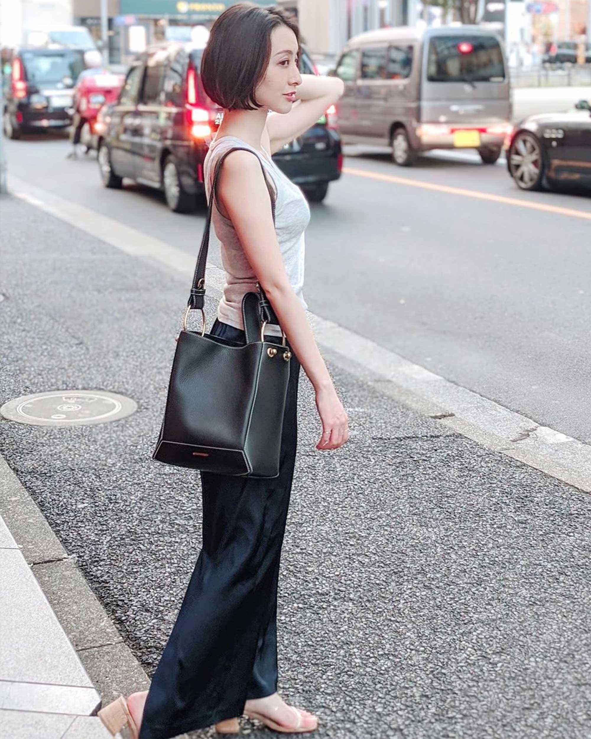 A woman walking down the street carrying a black purse